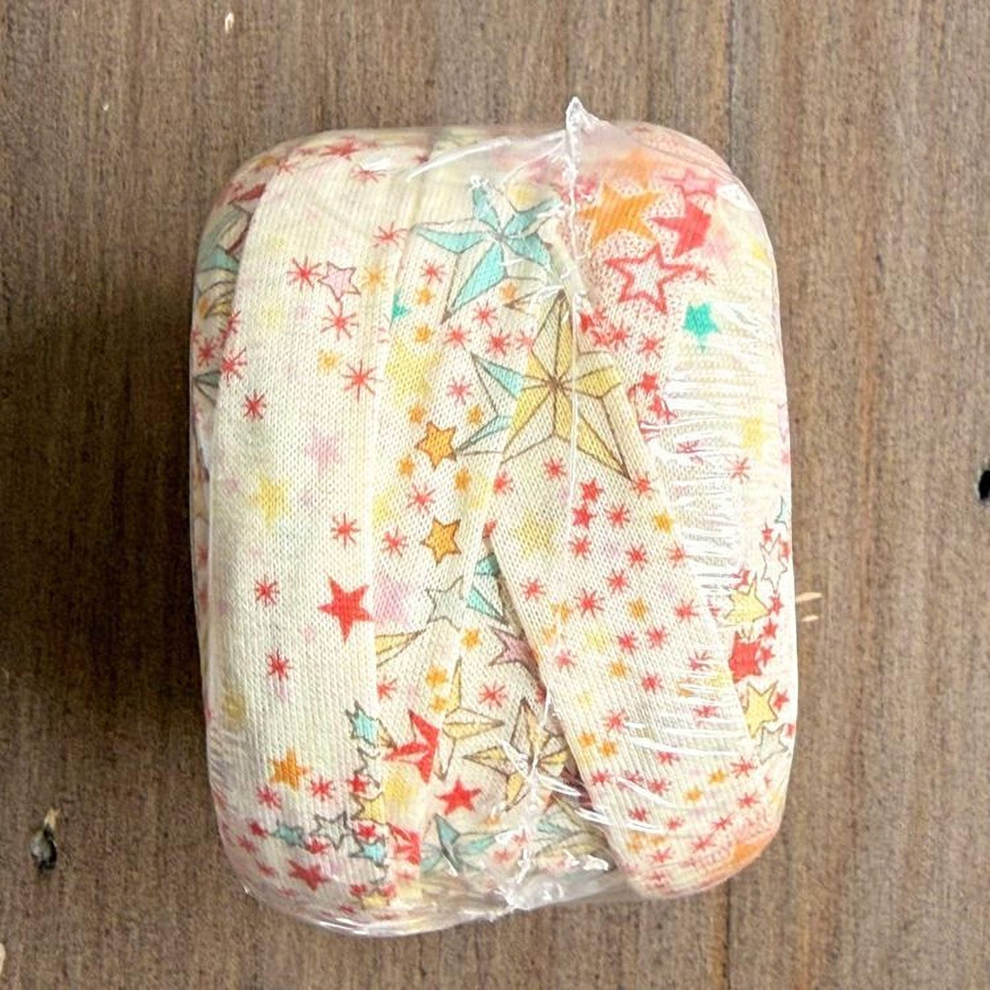 A wrapped object with a star-patterned fabric covering it, placed on a wooden surface.