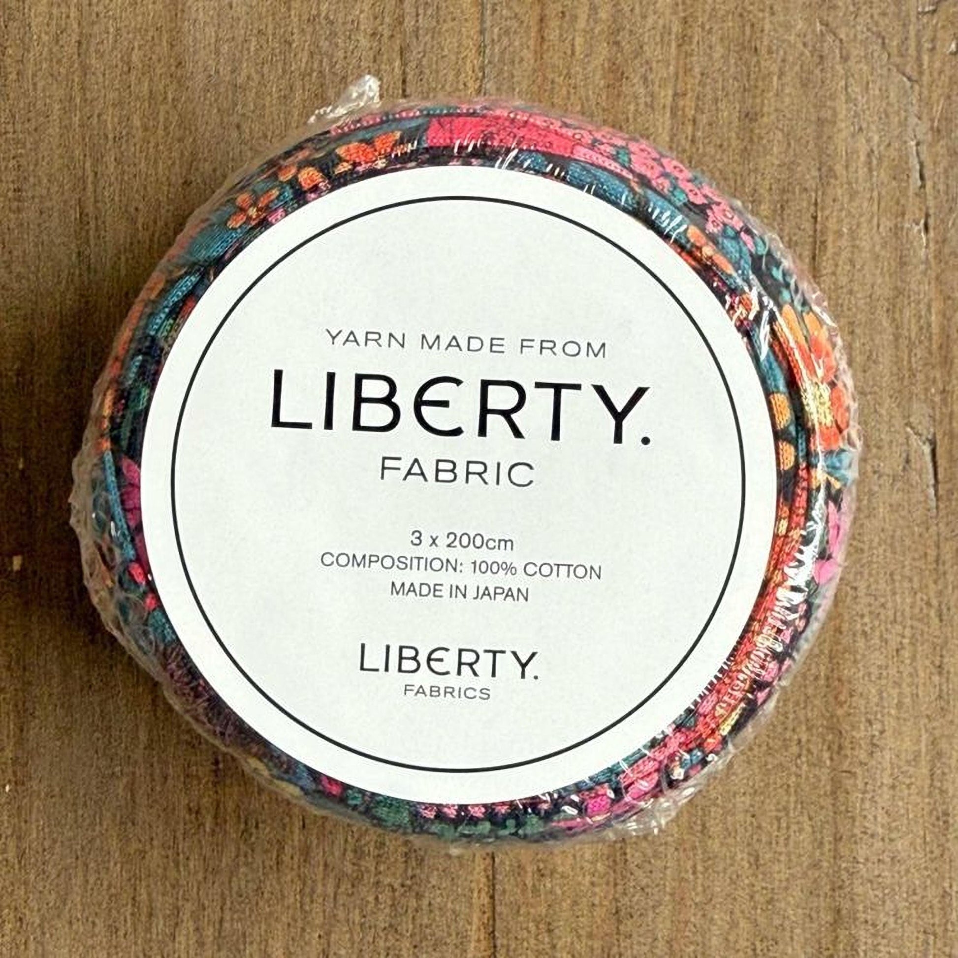 A circular object with a label that reads "Yarn Made from LIBERTY. FABRIC" and provides details about the product, including its composition and origin.