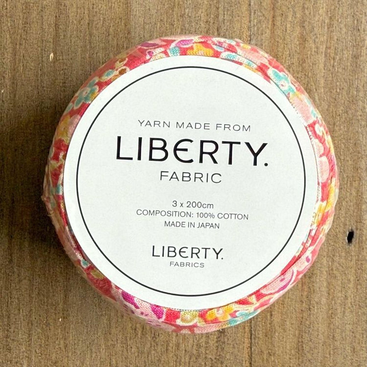 A round, white label with text and a floral pattern on a wooden surface.