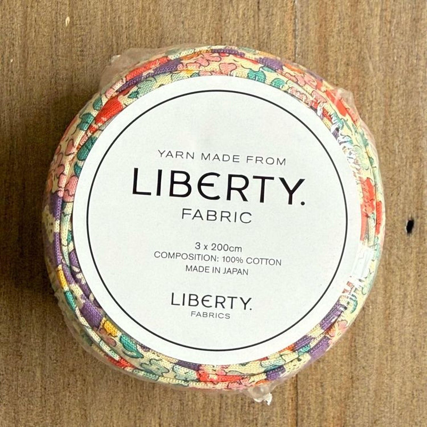 A spool of yarn made from Liberty fabric, with a label indicating it is made from 100% cotton and is manufactured in Japan.