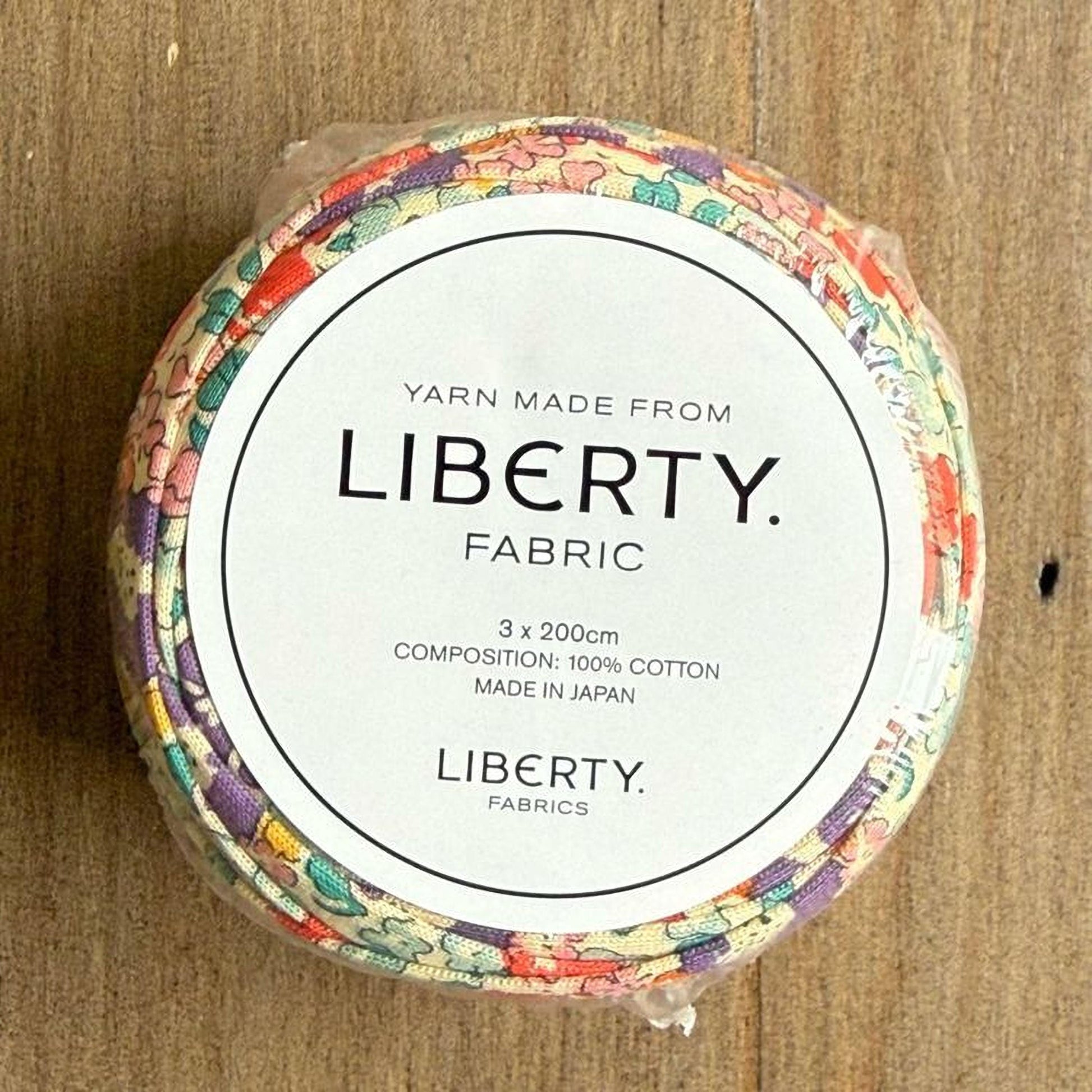 A spool of yarn made from Liberty fabric, with a label indicating it is made from 100% cotton and is manufactured in Japan.