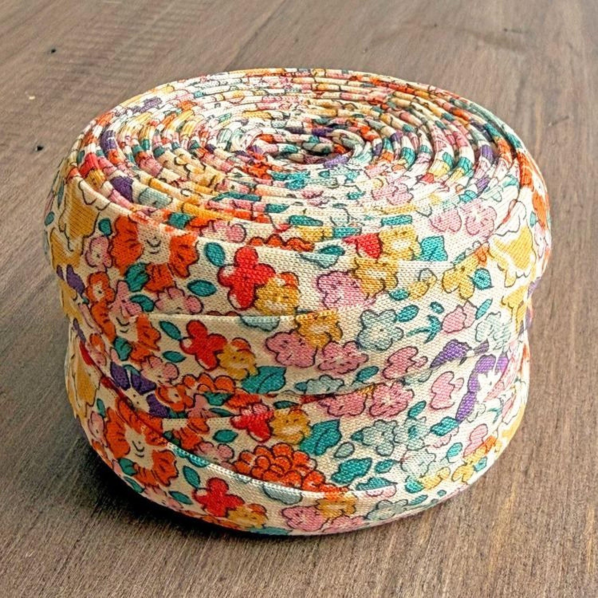 A colorful, floral-patterned fabric item, possibly a quilt or a decorative piece, is displayed on a wooden surface.