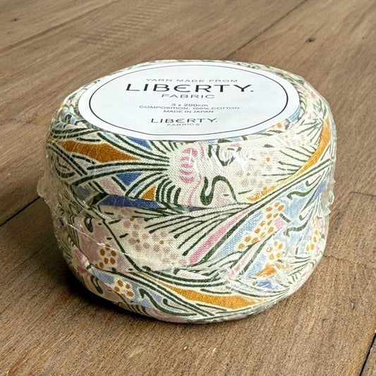 A package of Liberty yarn made from fabric, sitting on a wooden surface.