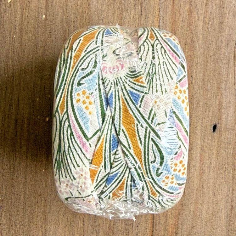 a colorful, patterned object, possibly a piece of fabric or paper, placed on a wooden surface.