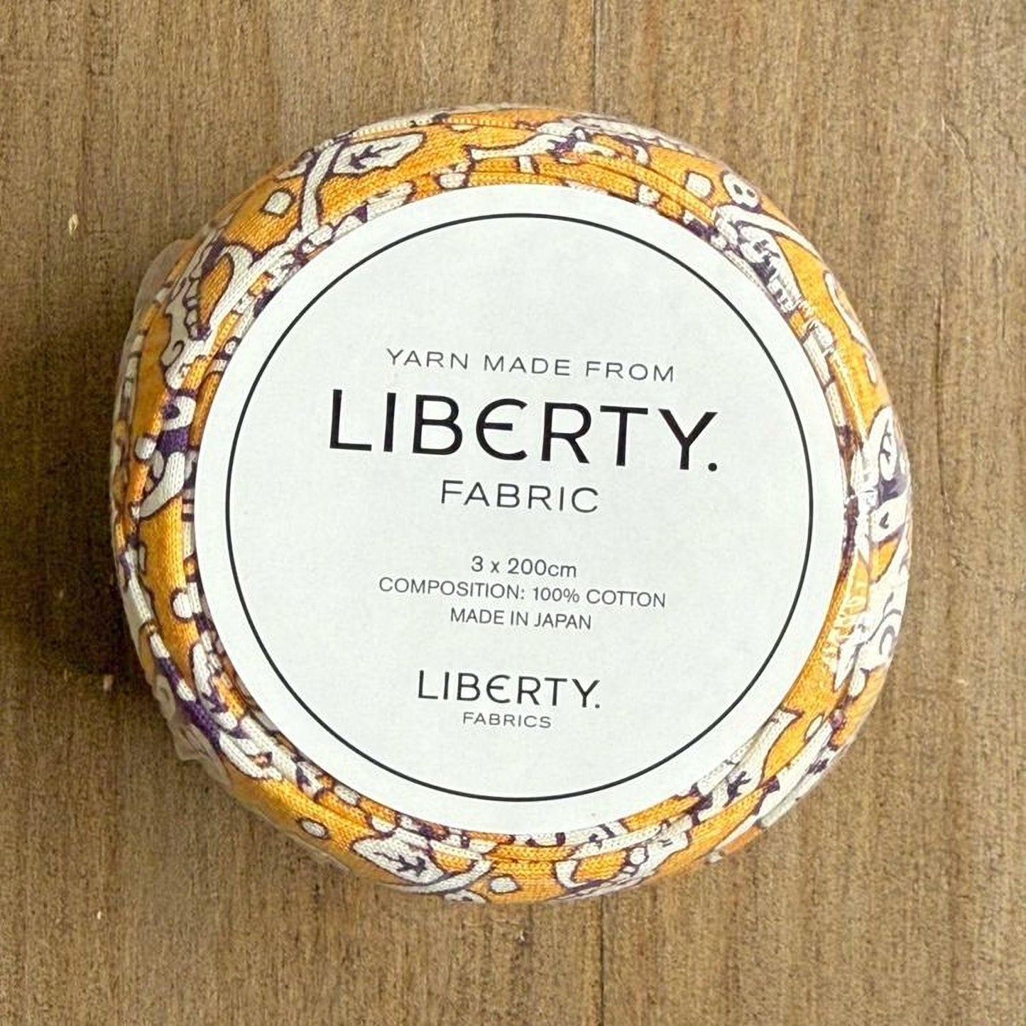 A circular object with a label that reads "YARN MADE FROM LIBERTY FABRIC".