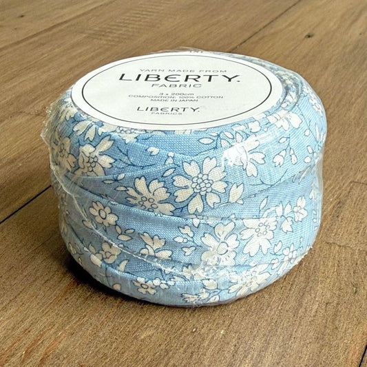 A blue and white floral fabric roll is sitting on a wooden surface.