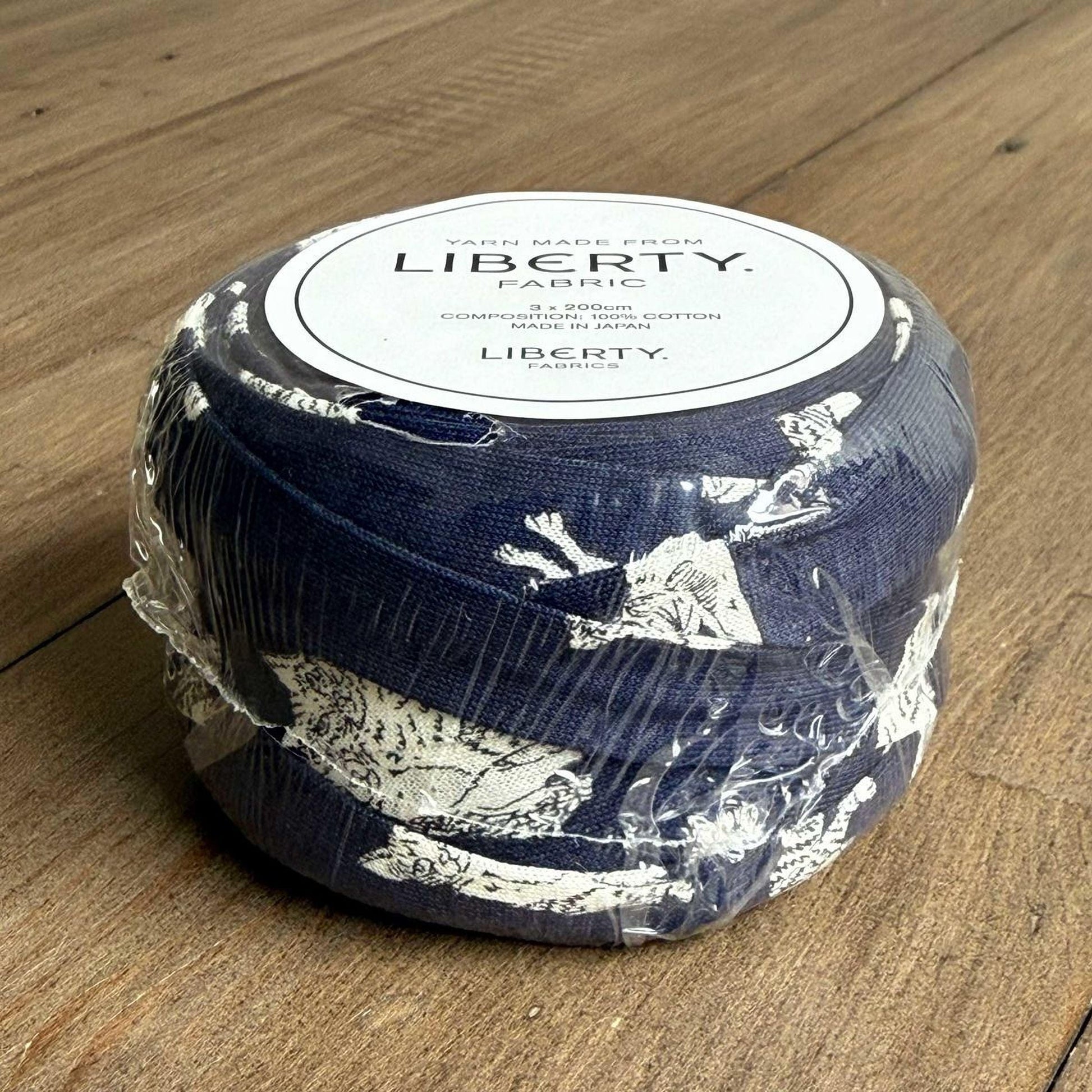 A blue and white fabric item wrapped in plastic, sitting on a wooden surface.