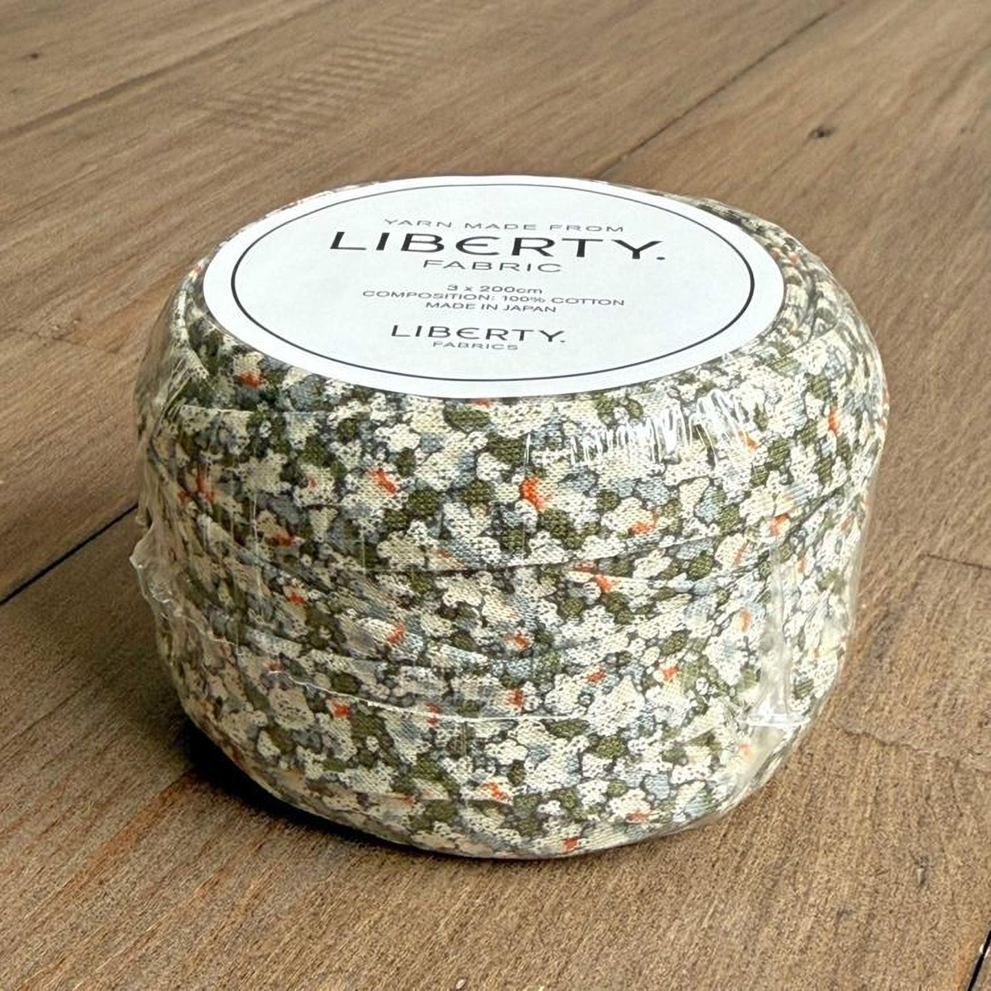 A package of fabric with a floral pattern, sitting on a wooden surface.