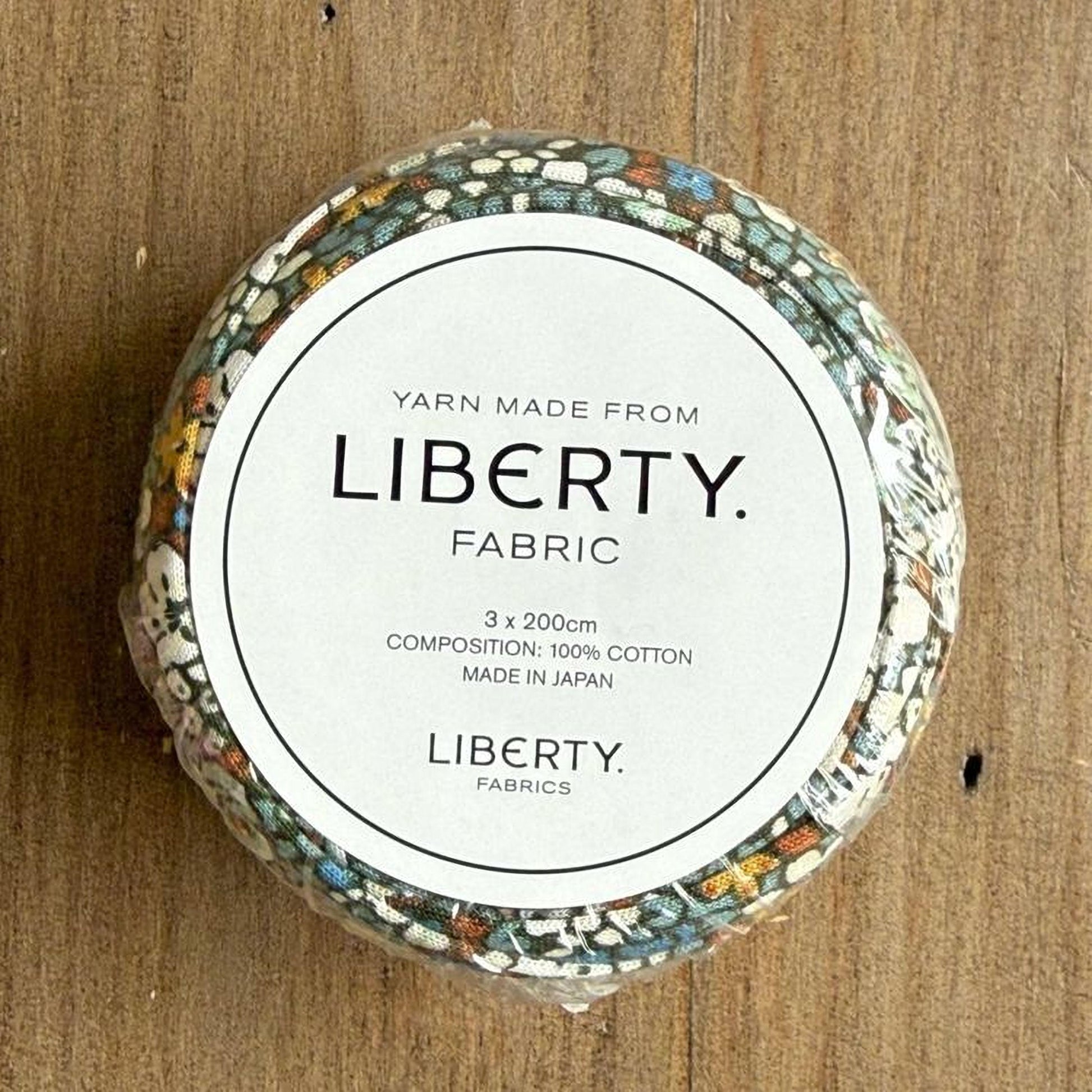 A round, white label with text and a floral pattern on a wooden surface.