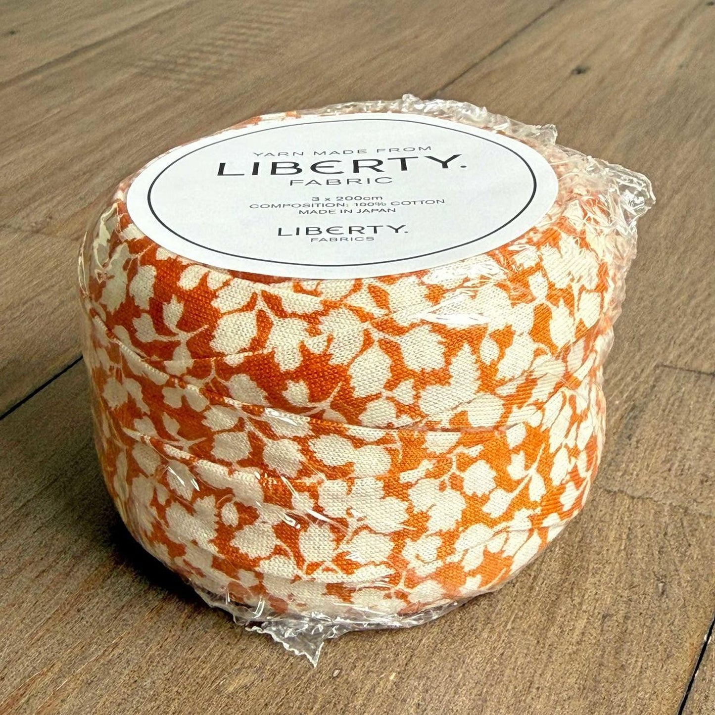 A package of Liberty fabric, featuring a floral pattern in shades of orange and white.