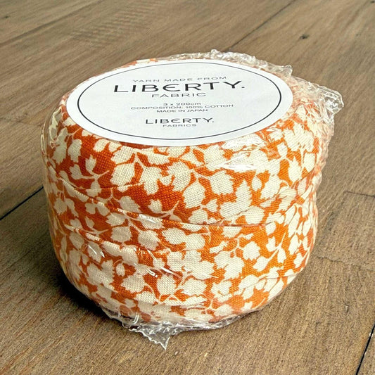 A package of Liberty fabric, featuring a floral pattern in shades of orange and white.
