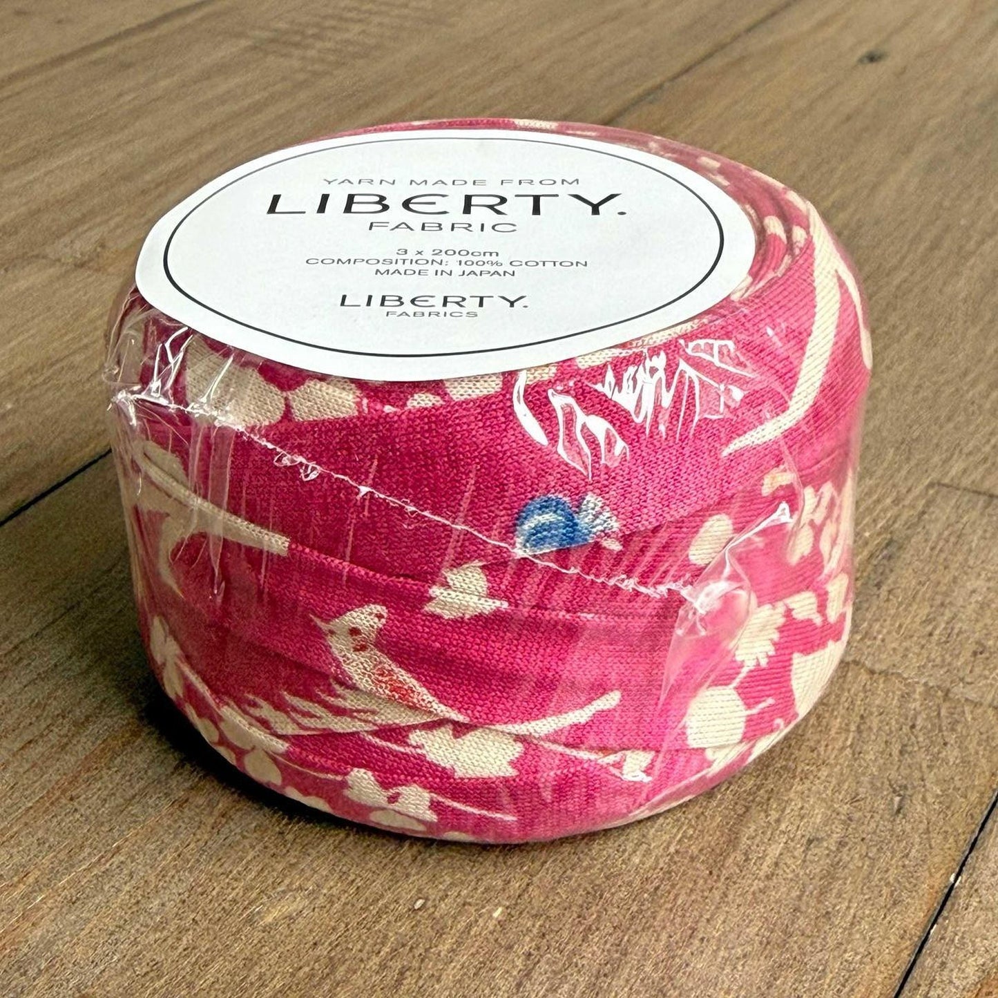 A roll of yarn with a pink and white floral pattern, labeled as "Liberty Fabric" and "Yarn Made from Liberty".