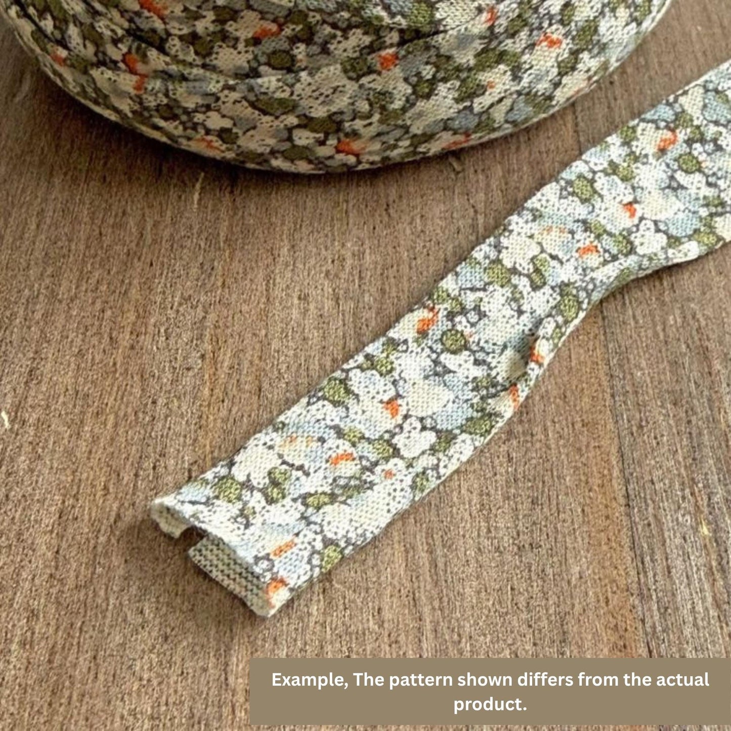 a piece of fabric with a floral pattern, lying on a wooden surface. The pattern on the fabric appears to differ from the actual product, as described in the caption.