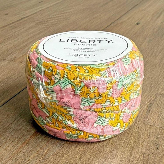 A package of fabric spools with a floral print design, sitting on a wooden surface.