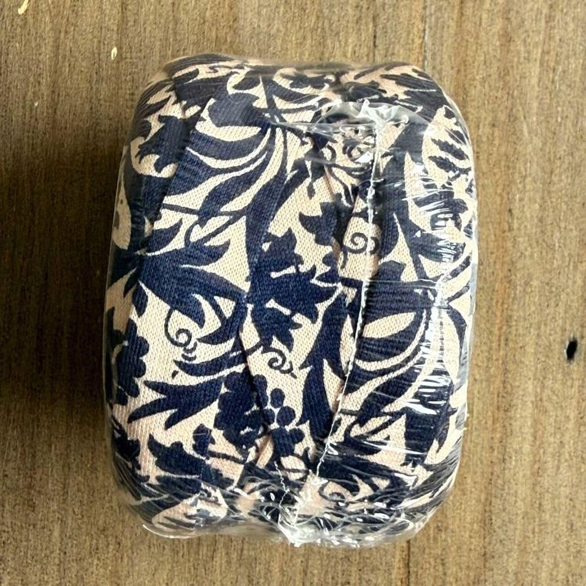 A wrapped object with a blue and white floral pattern, sitting on a wooden surface.