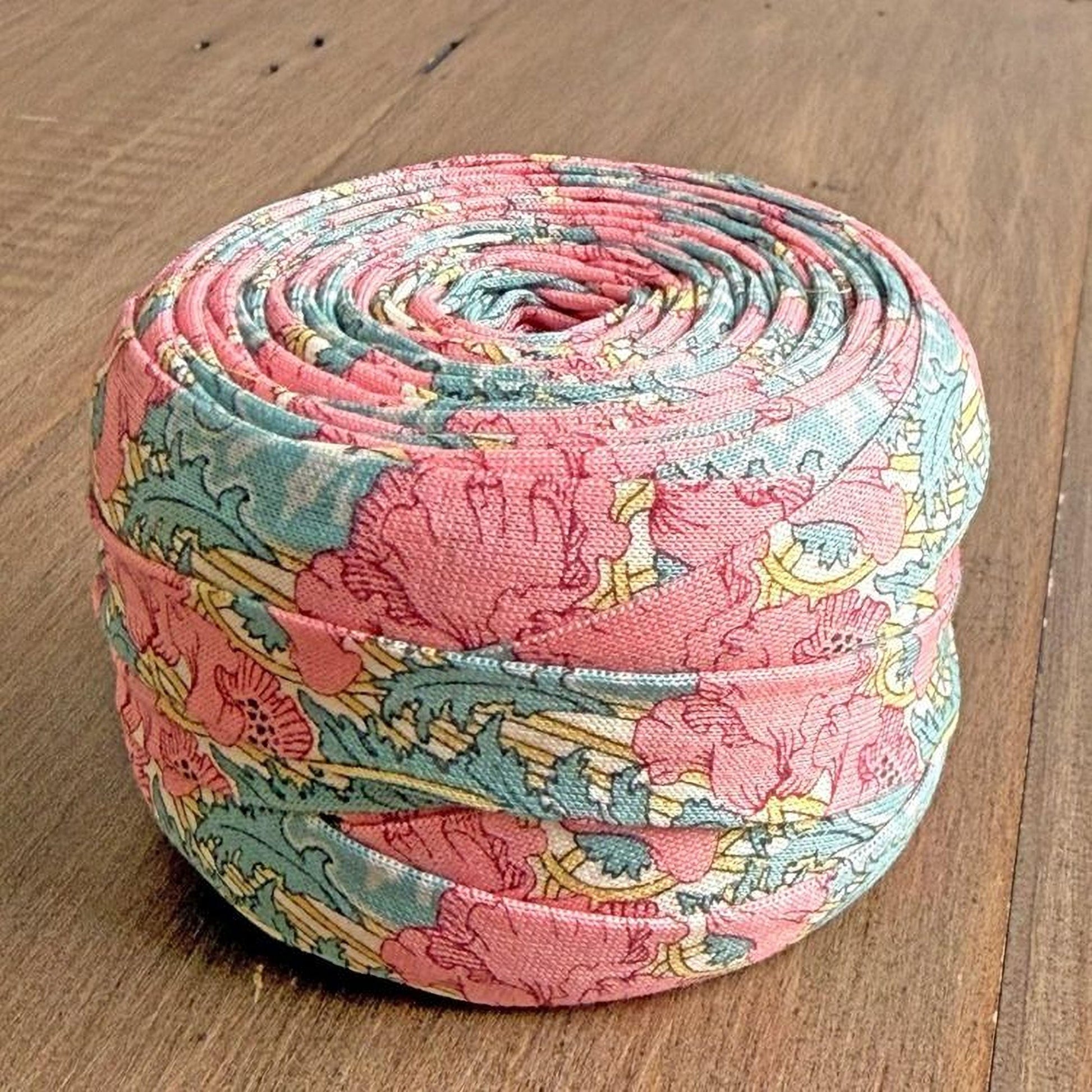 A colorful, rolled-up spool of fabric with a floral pattern in shades of pink, blue, and green.
