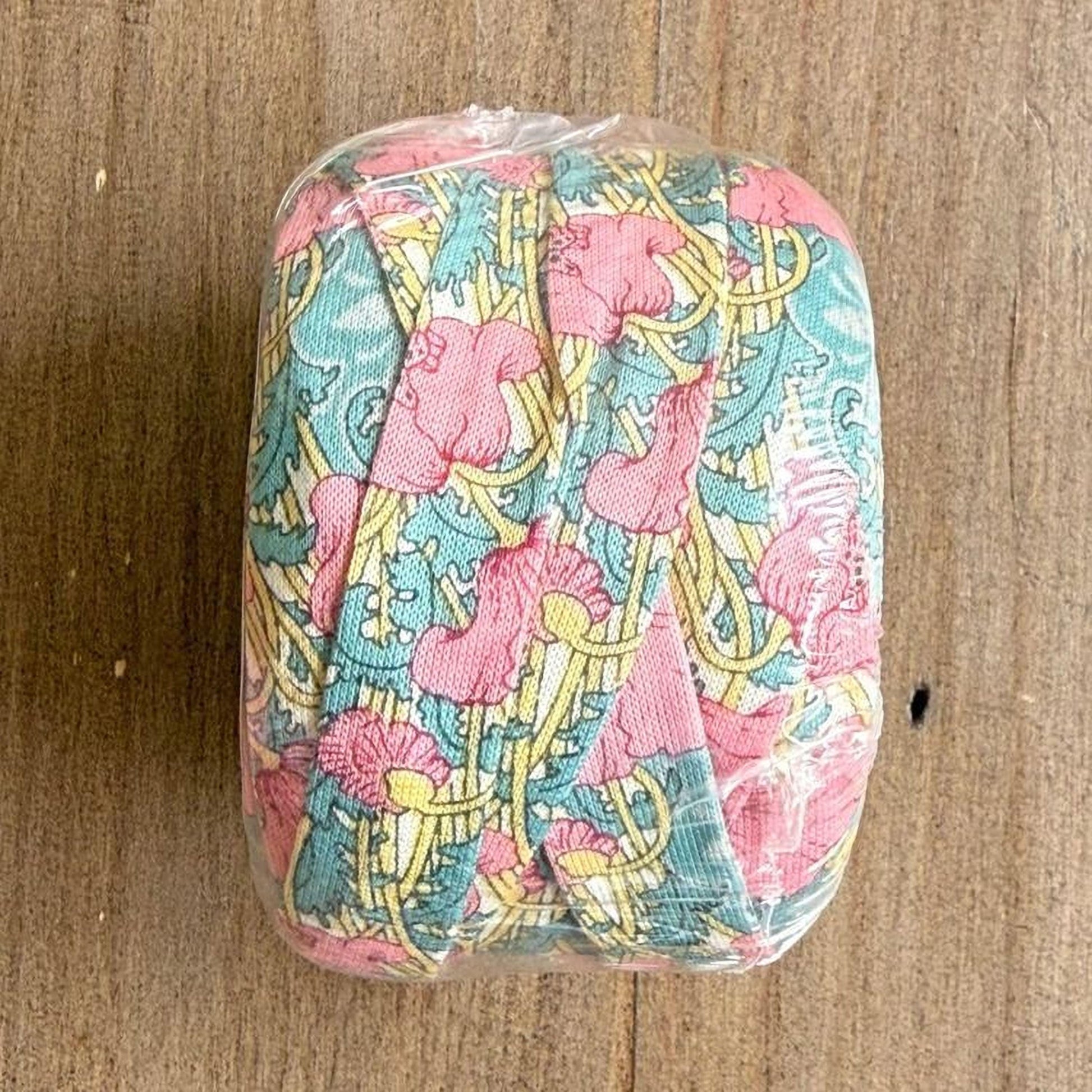 A clear plastic bag containing a colorful fabric with a floral pattern in shades of pink, blue, and yellow.