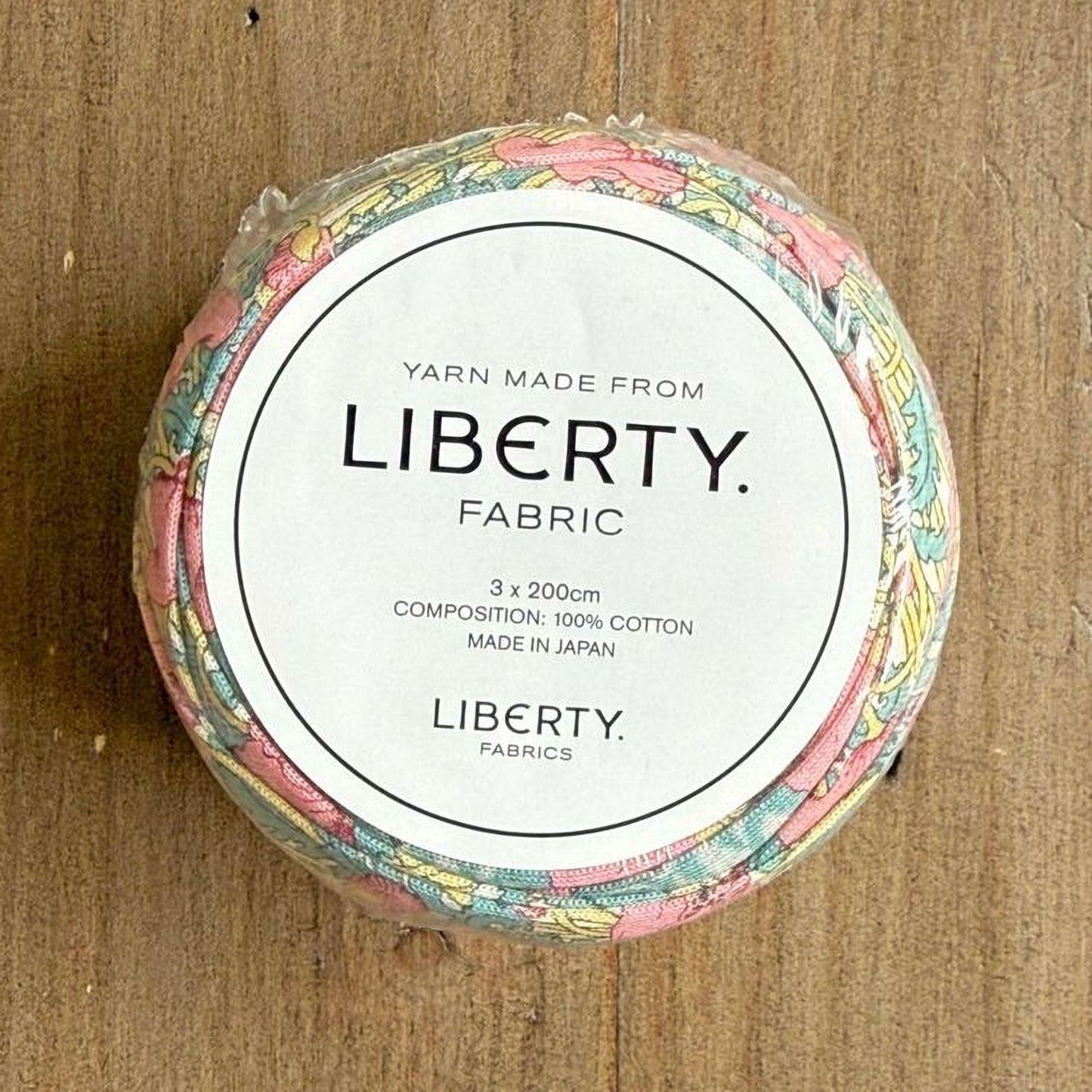 A circular spool of yarn with a label that reads "Yarn Made from LIBERTY. FABRIC. 3 x 200cm COMPOSITION: 100% COTTON MADE IN JAPAN".
