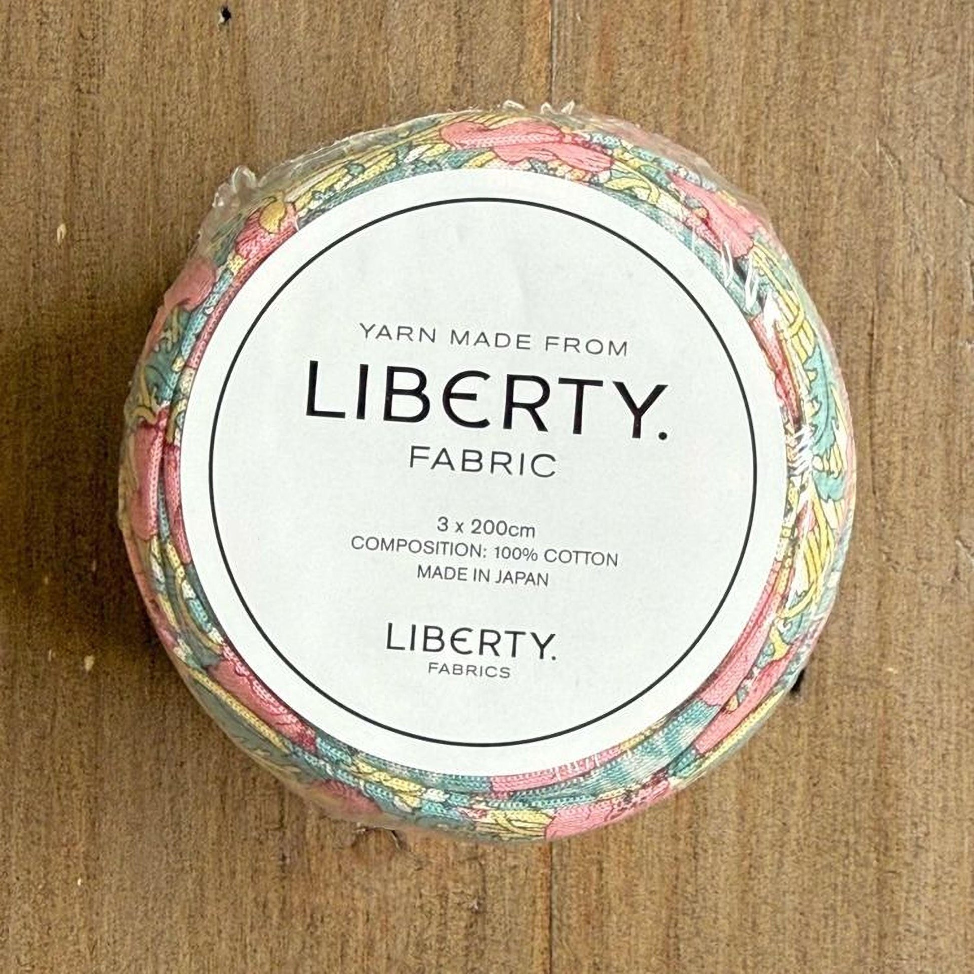 A circular spool of yarn with a label that reads "Yarn Made from LIBERTY. FABRIC. 3 x 200cm COMPOSITION: 100% COTTON MADE IN JAPAN".