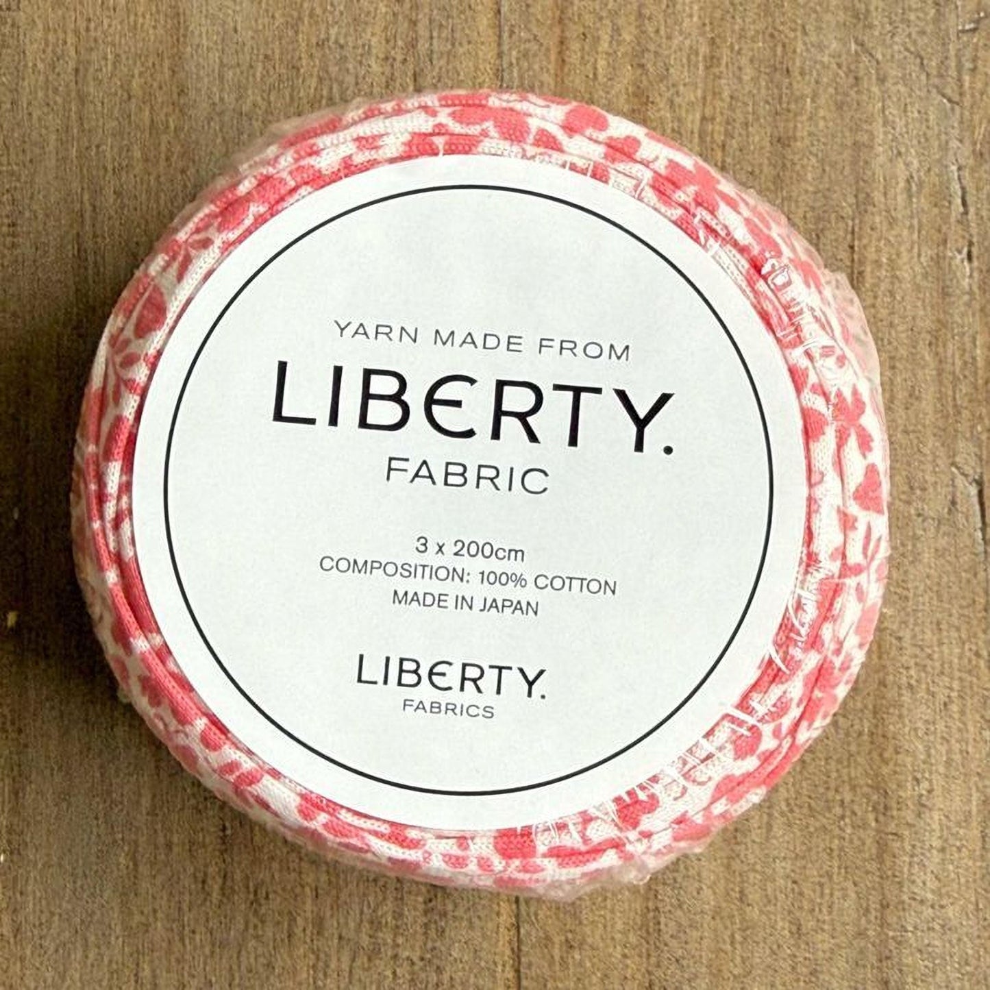 A white label with black text on a red and white fabric-covered object, which appears to be a spool of yarn.