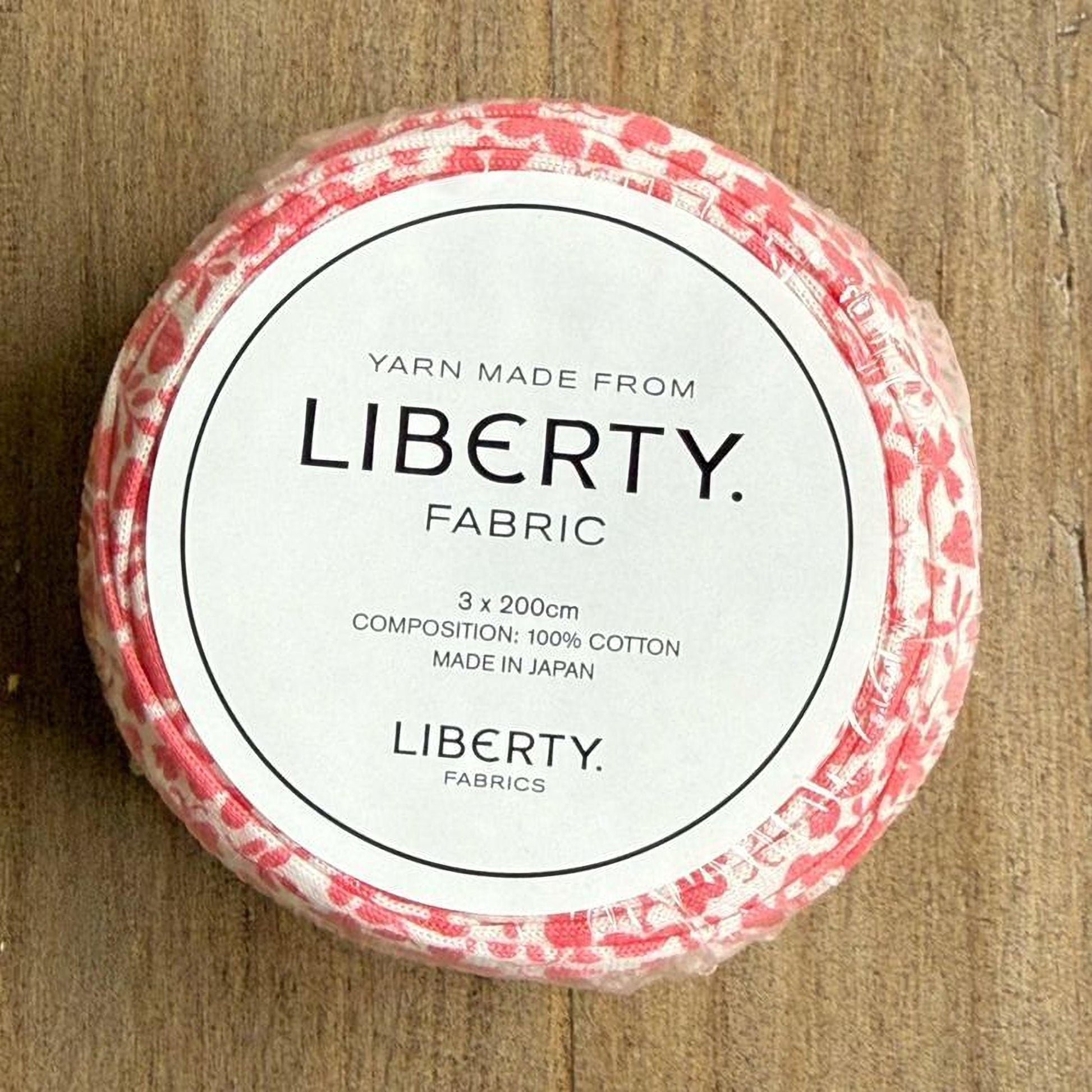 A white label with black text on a red and white fabric-covered object, which appears to be a spool of yarn.