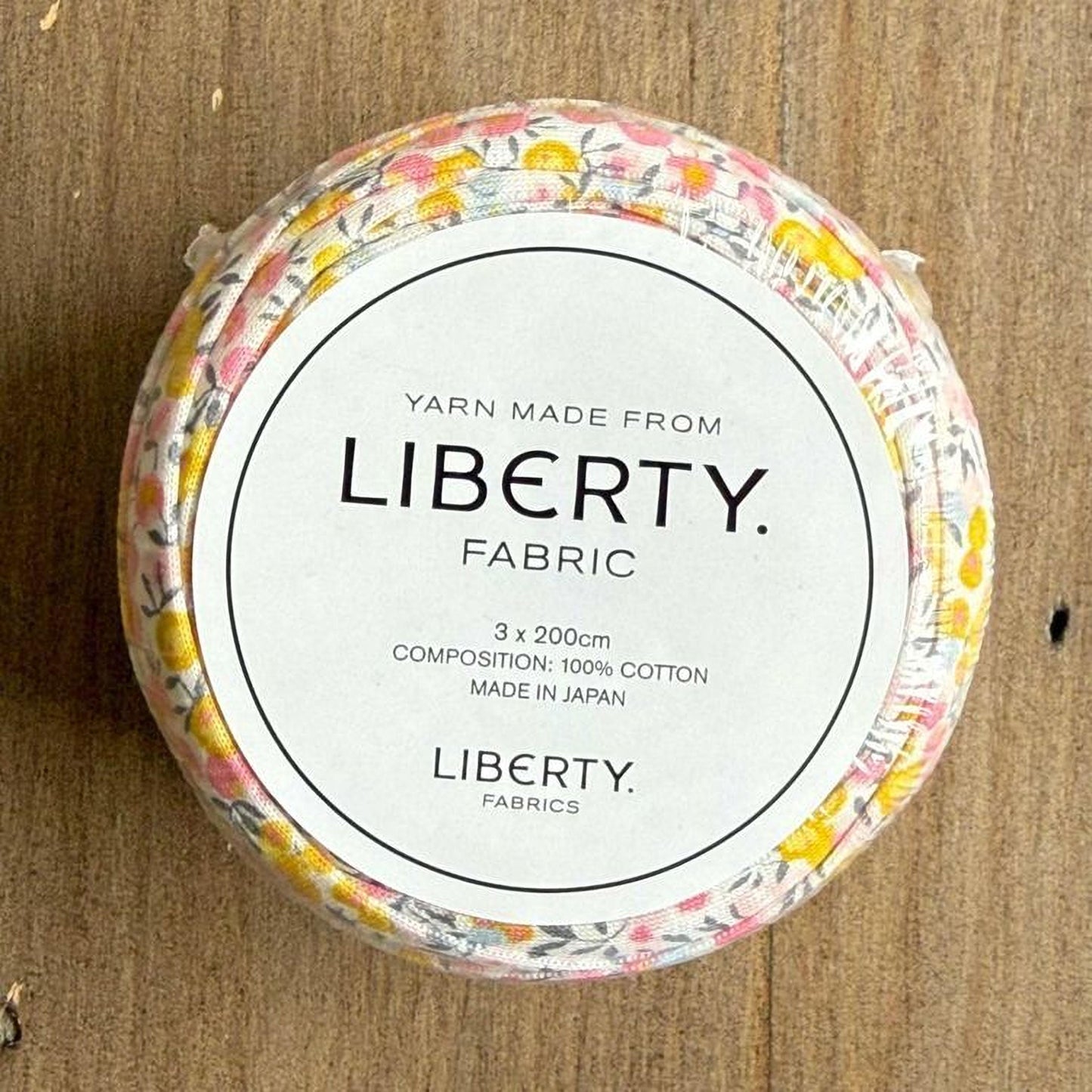 A round container with a label that reads "Yarn Made from LIBERTY FABRIC" and provides details about the product, including its composition and manufacturing origin.
