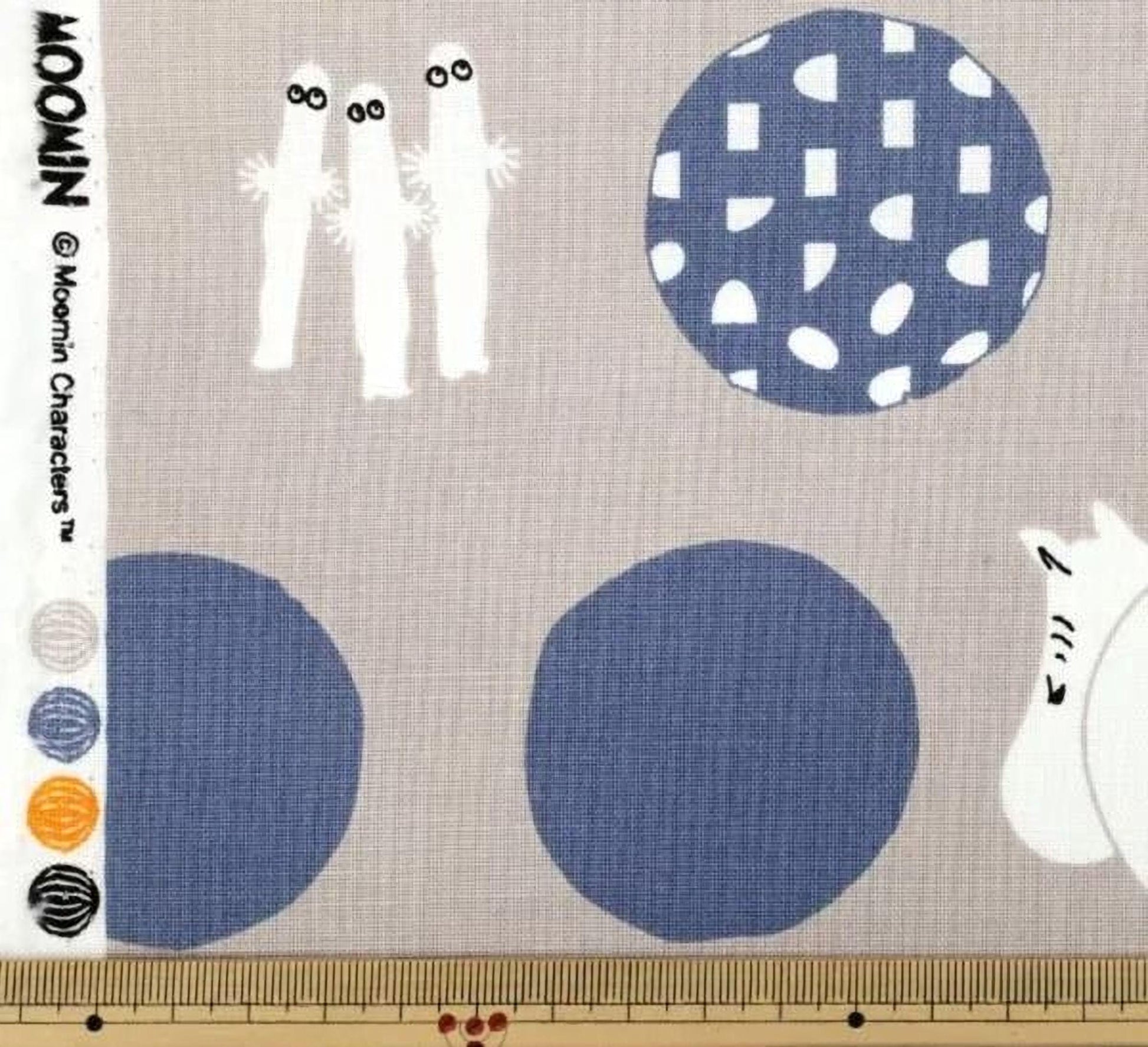 The image is a fabric with various patterns and designs, including circles, dots, and silhouettes of people.