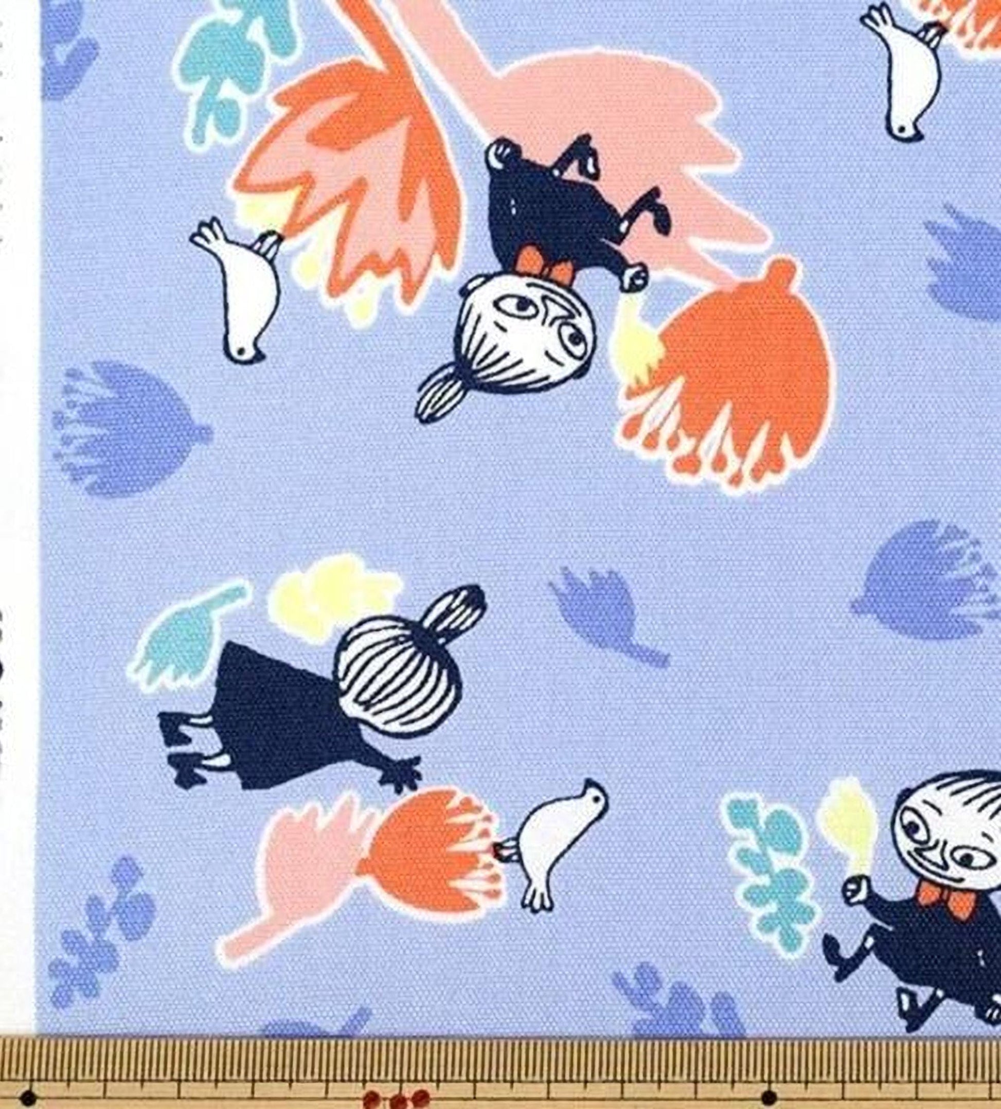 The image is a fabric print featuring a whimsical scene with various cartoon-like characters, including a bird, flowers, and other whimsical elements. The print is predominantly blue and orange, with the characters and flowers in shades of blue and orange. The image is a collage of multiple images, and the text "KOKKA CO., LTD." is visible, indicating the brand of the fabric print.