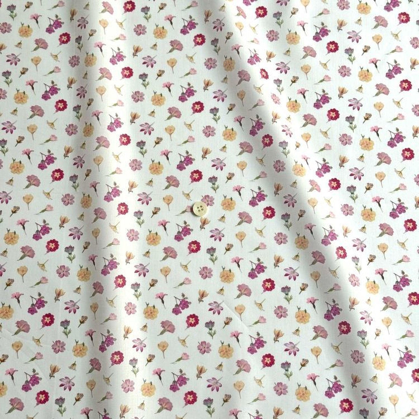 a fabric with a repeating pattern of various colorful flowers, including pink, yellow, and purple flowers, against a white background.