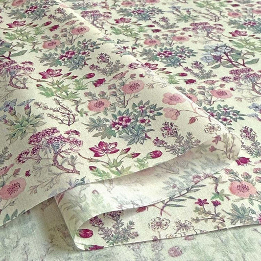 a close-up view of a fabric with a floral pattern, including various types of flowers and leaves in shades of pink, green, and purple.