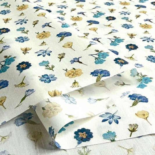 a close-up view of a fabric with a repeating floral pattern in shades of blue and yellow. The pattern consists of various flowers and leaves, creating a visually appealing and intricate design.