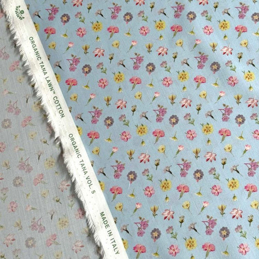 a fabric with a floral pattern, featuring various types of flowers in different colors and sizes. The fabric appears to be made of cotton and is displayed on a white fabric with a fringe.
