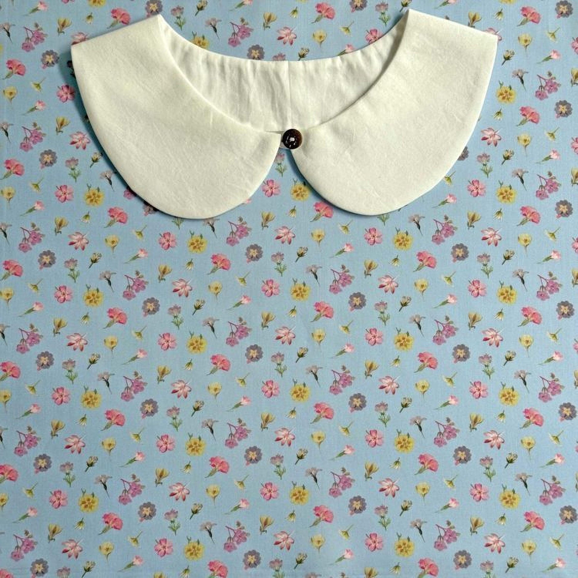 a white collar with a button, set against a background of a blue floral print.