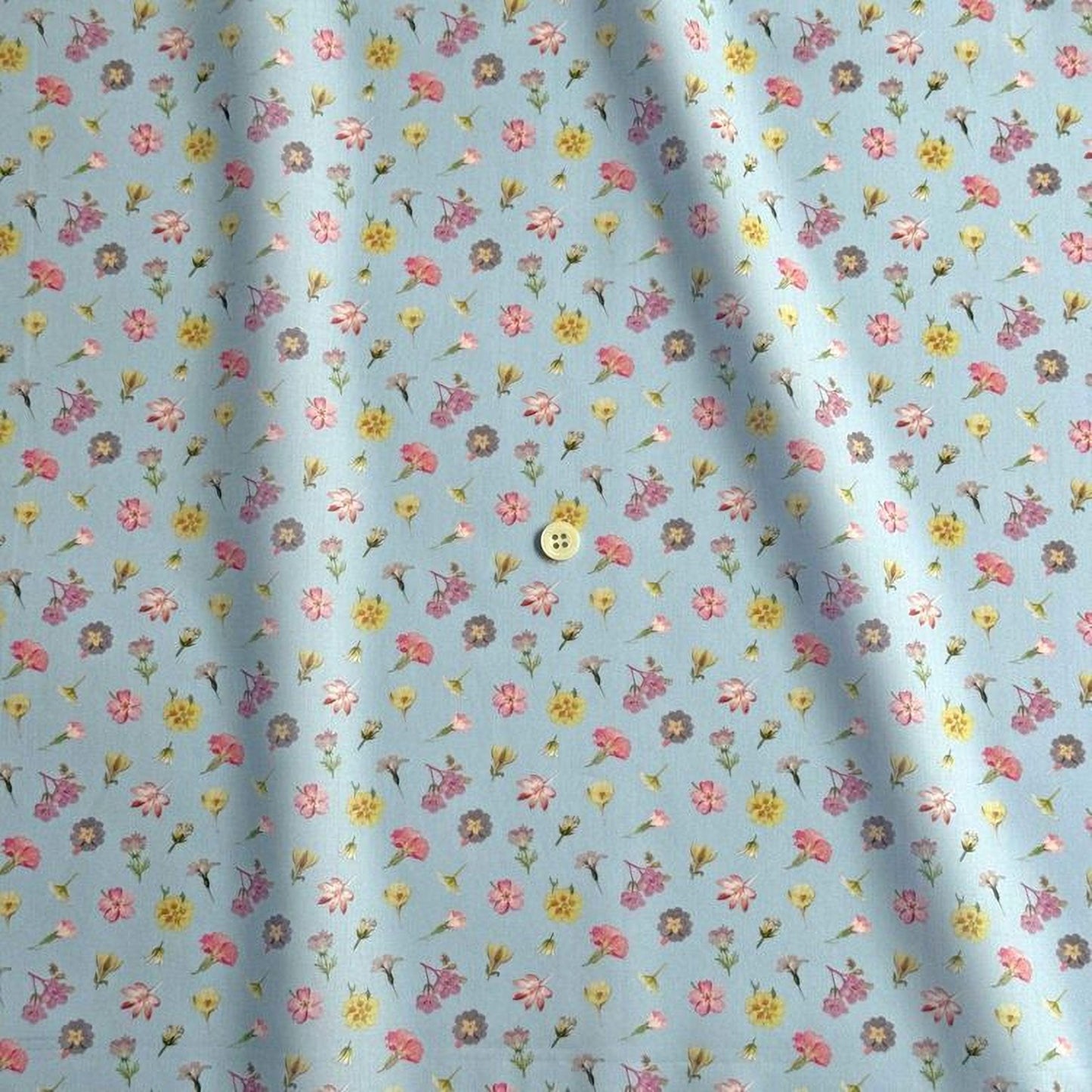 a fabric with a repeating pattern of small flowers in various colors, including pink, yellow, and purple. The pattern is spread across the fabric, creating a visually appealing and colorful design.