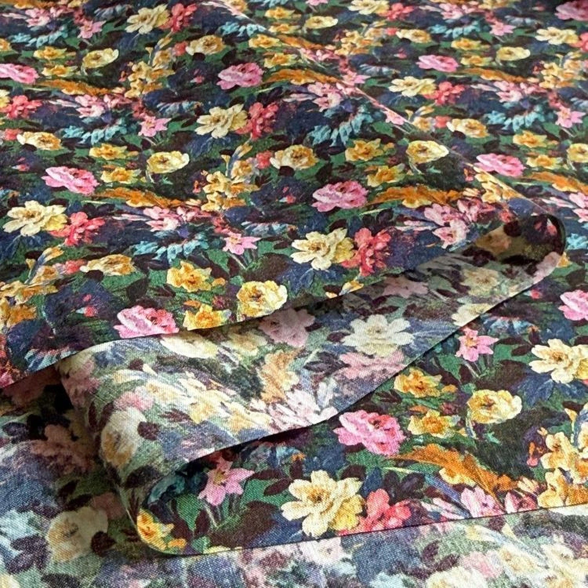 a close-up view of a fabric with a vibrant floral pattern. The fabric appears to be a blend of various colors, including shades of green, pink, yellow, and blue, creating a visually striking and intricate design.