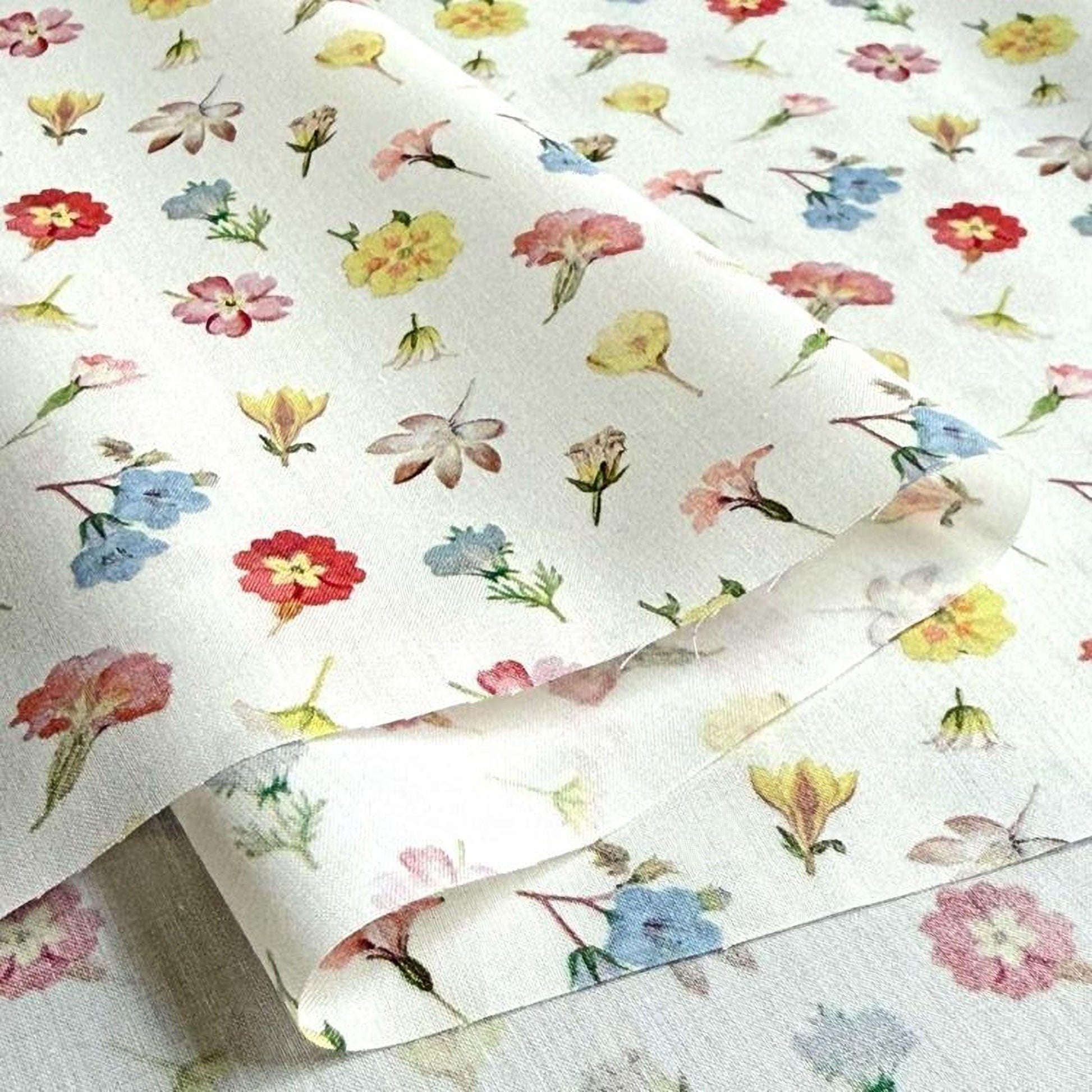a close-up view of a fabric with a repeating floral pattern. The pattern consists of various types of flowers, including roses, daisies, and other colorful blooms, arranged in a visually appealing manner. The fabric appears to be a piece of paper or a textile, with the flowers printed on it in a vibrant and detailed manner.