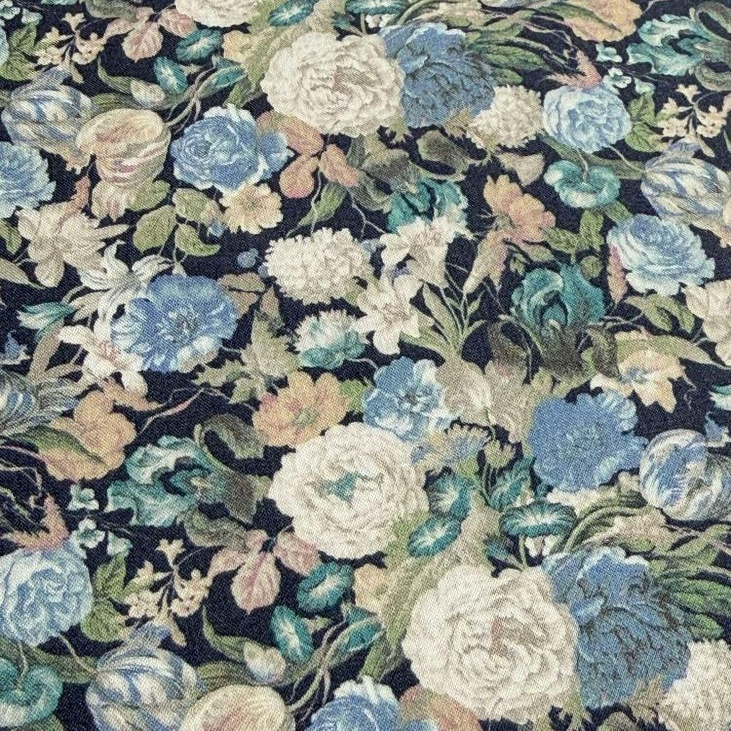 The image is a close-up of a fabric with a floral pattern, featuring a variety of colorful flowers and leaves in shades of blue, white, and green.