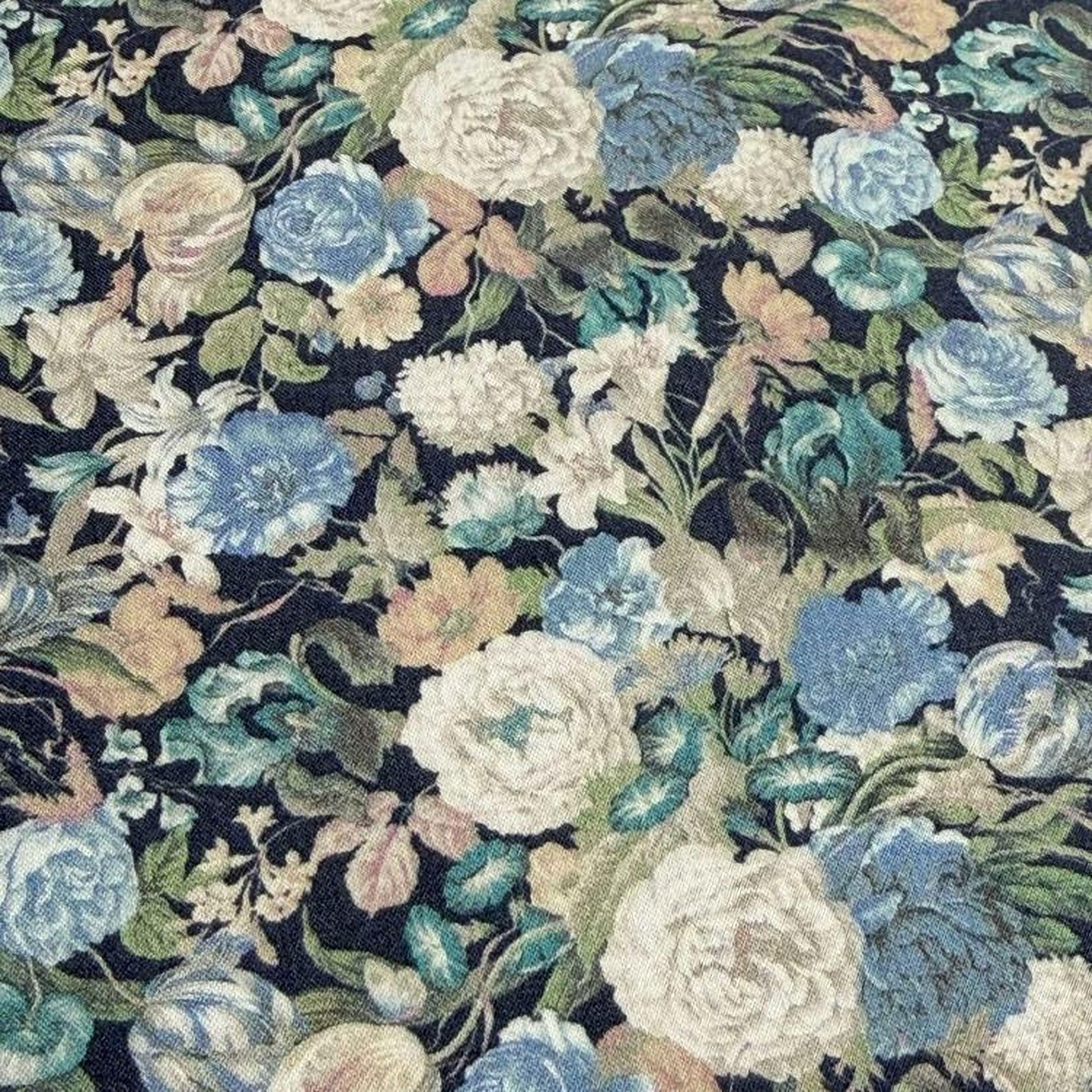 The image is a close-up of a fabric with a floral pattern, featuring a variety of colorful flowers and leaves in shades of blue, white, and green.