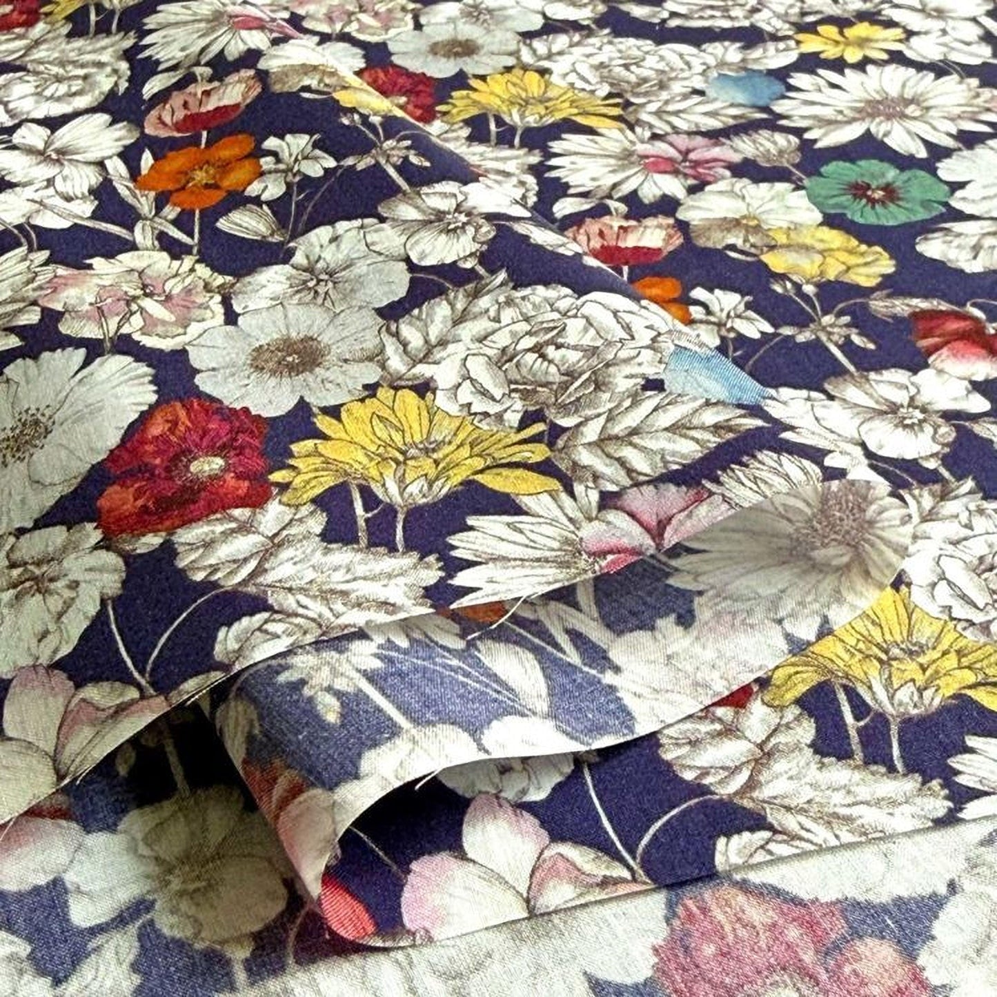a close-up view of a fabric with a vibrant floral pattern. The fabric is predominantly blue and white, with various colorful flowers such as red, yellow, and pink flowers scattered across the fabric. The flowers are detailed and intricately designed, creating a visually striking and eye-catching pattern.