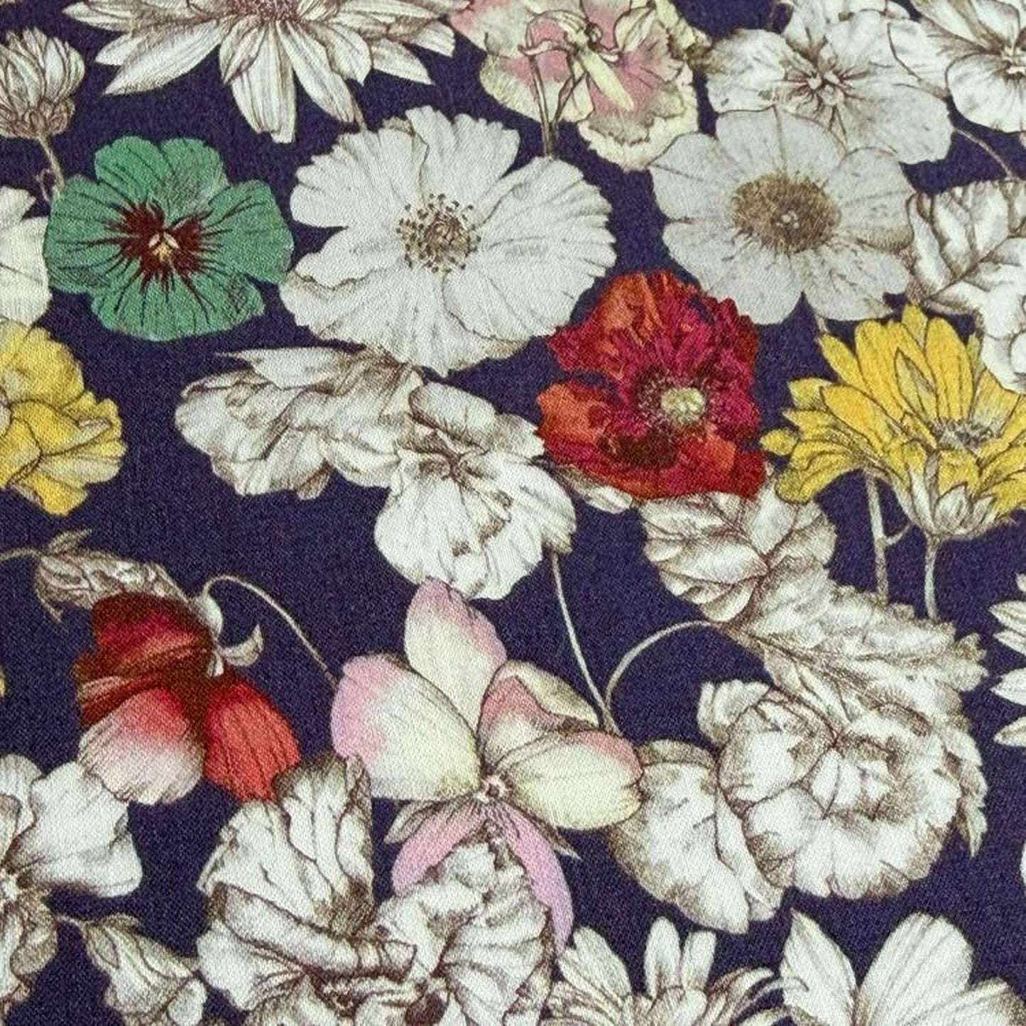 a close-up view of a fabric with a floral pattern. The fabric is adorned with a variety of colorful flowers, including white, red, yellow, and pink flowers, all intricately detailed and overlapping each other. The flowers are arranged in a visually appealing manner, creating a vibrant and lively pattern on the fabric.