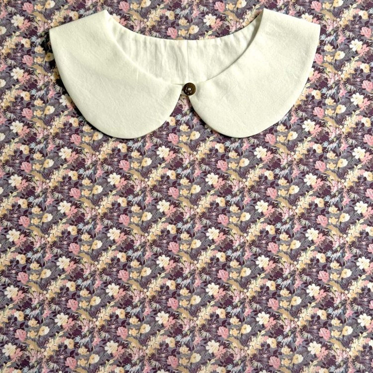 A white collar is displayed on a floral print fabric.