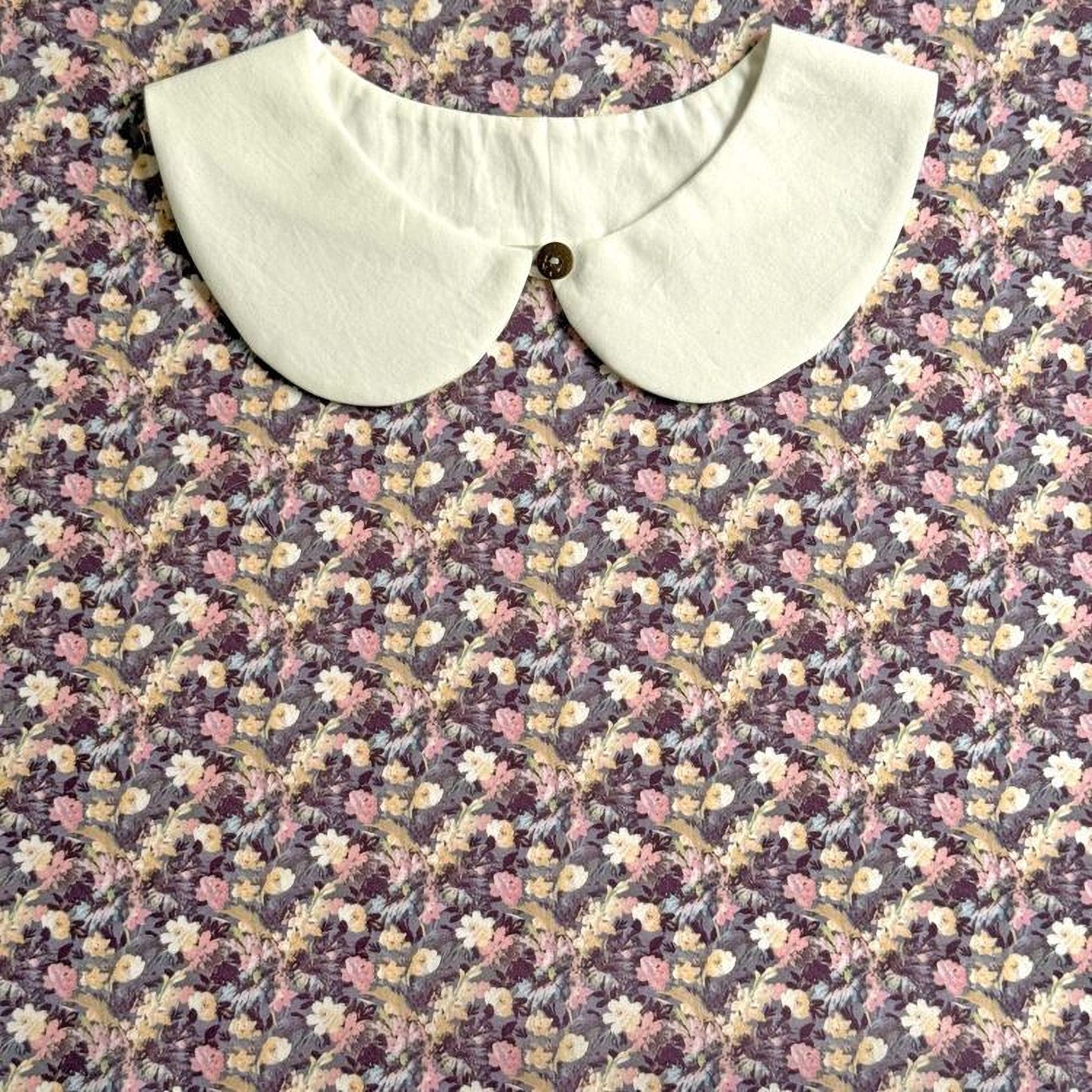 A white collar is displayed on a floral print fabric.