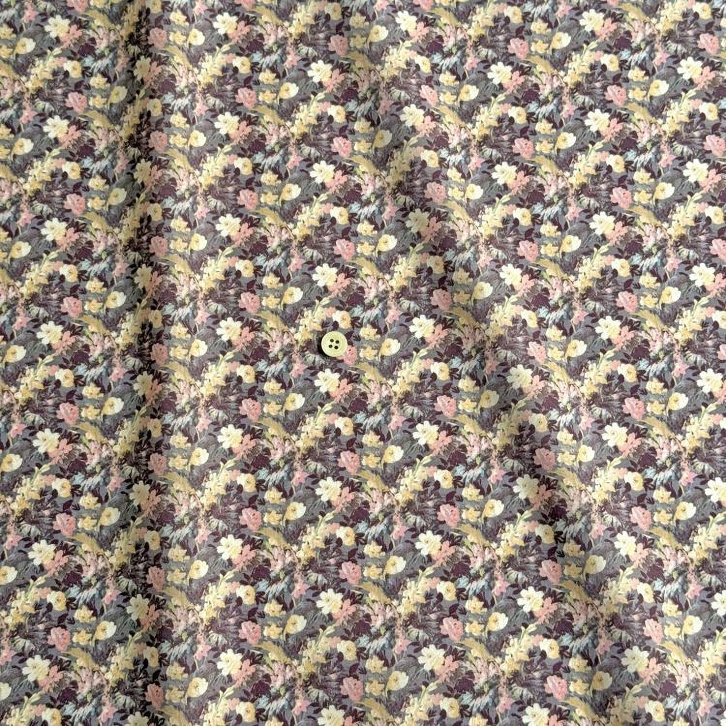 a close-up view of a fabric with a floral pattern, featuring a small button in the center.