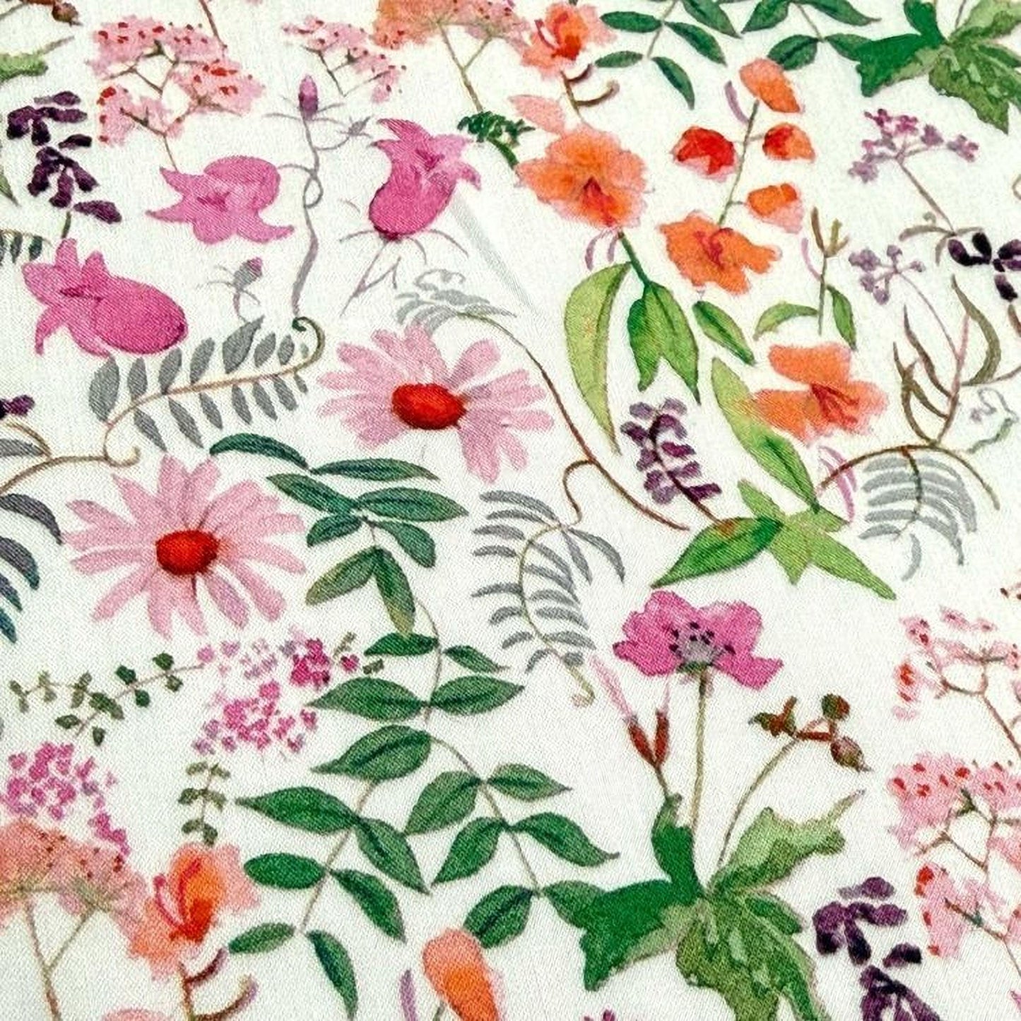 The image is a close-up of a fabric with a vibrant floral pattern. The pattern consists of various flowers and leaves in shades of pink, orange, and green, creating a visually appealing and colorful design.