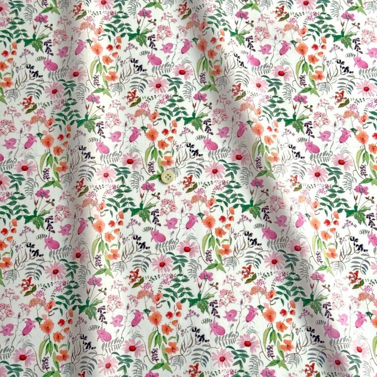 a close-up view of a fabric with a floral pattern. The pattern consists of various flowers and leaves in different colors, including pink, orange, green, and purple. The fabric appears to be made of a soft, white material, and the pattern is intricate and detailed.