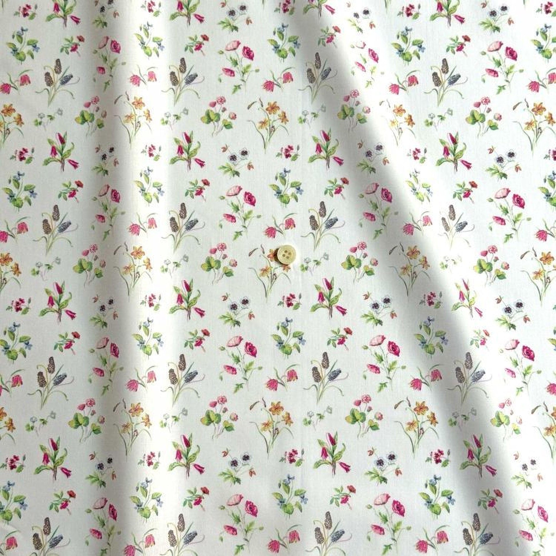 a close-up view of a fabric with a repeating floral pattern in shades of pink, green, and yellow. The pattern is composed of various flowers and leaves, creating a visually appealing and intricate design. The fabric appears to be made of a soft, light-colored material, suitable for clothing or home decor.