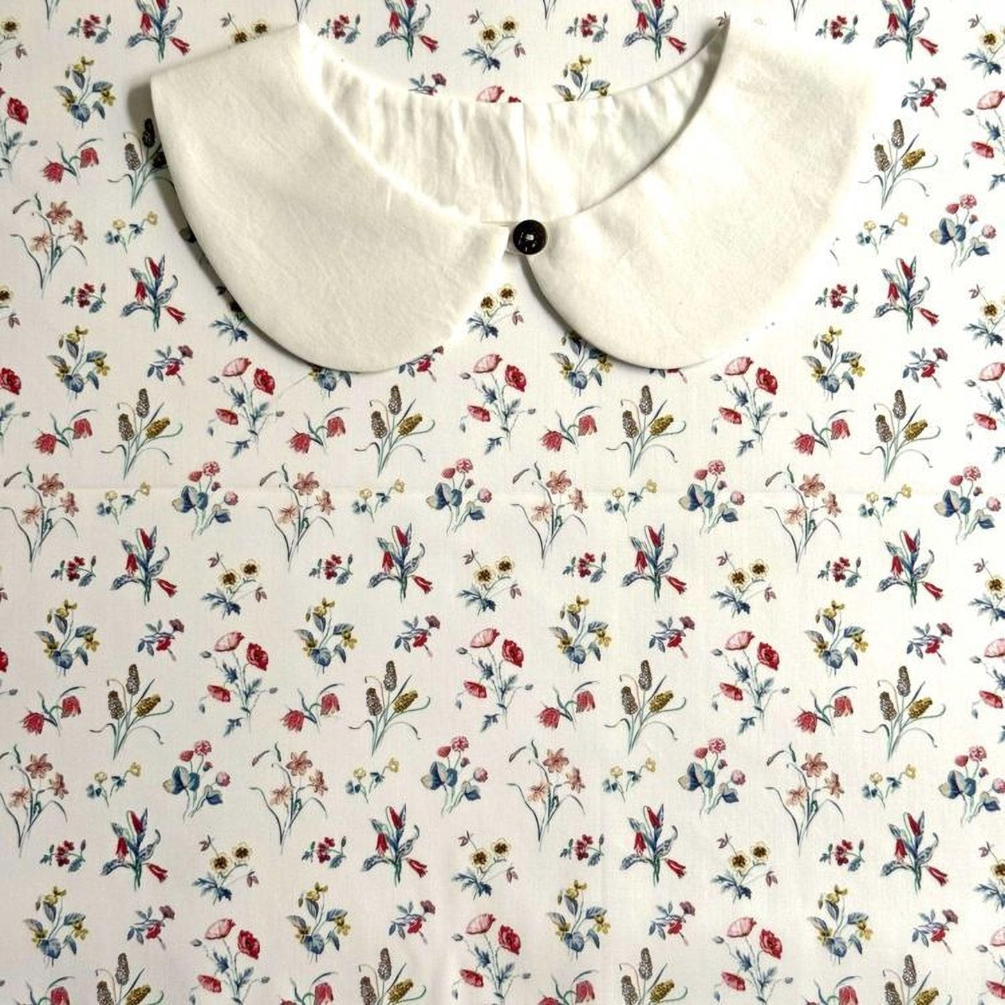 a white collar with a button, set against a background with a floral print.