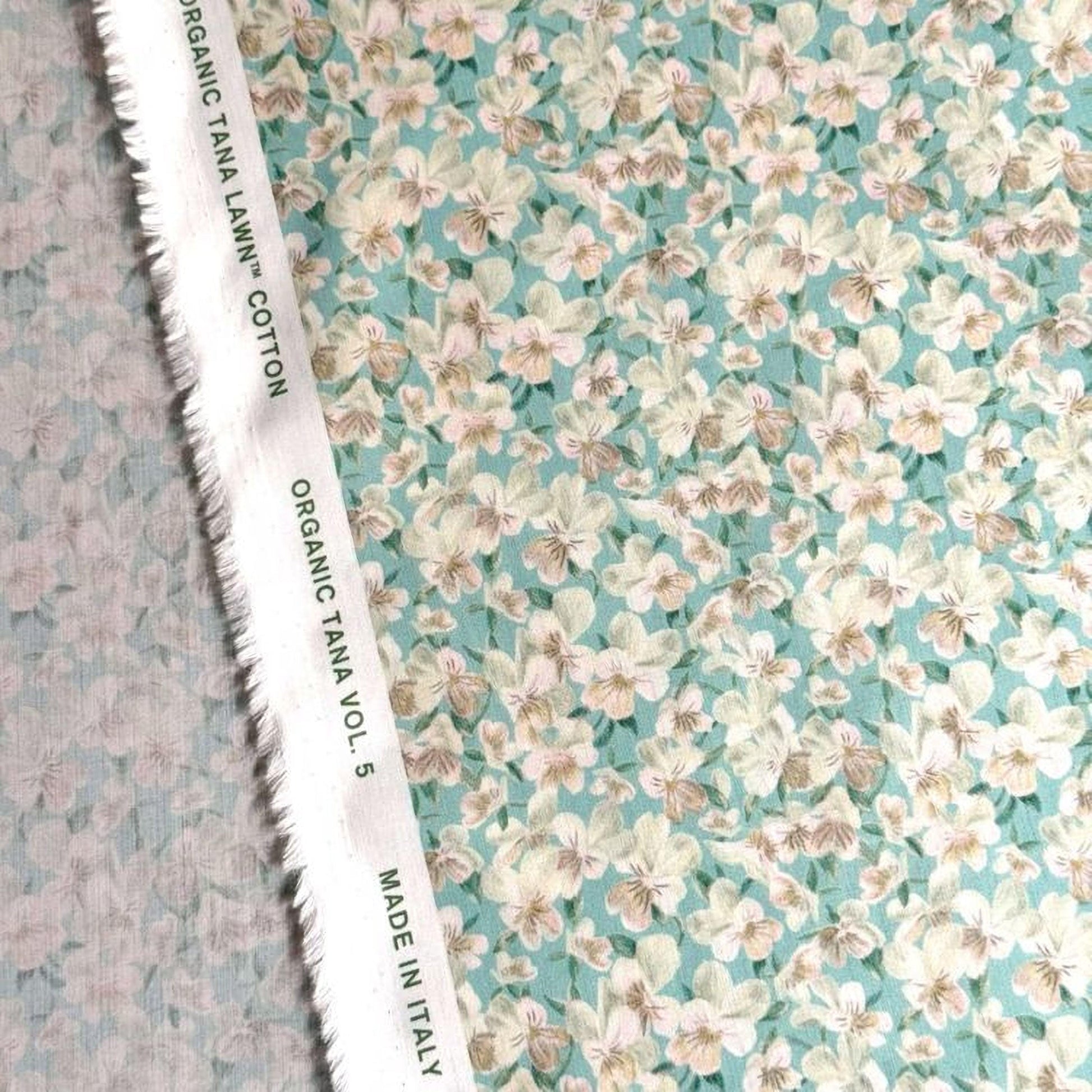 a close-up view of a fabric with a floral pattern in shades of green and white. The fabric appears to be made of organic cotton and is labeled as "Organic Tana Cotton" and "Made in Italy".