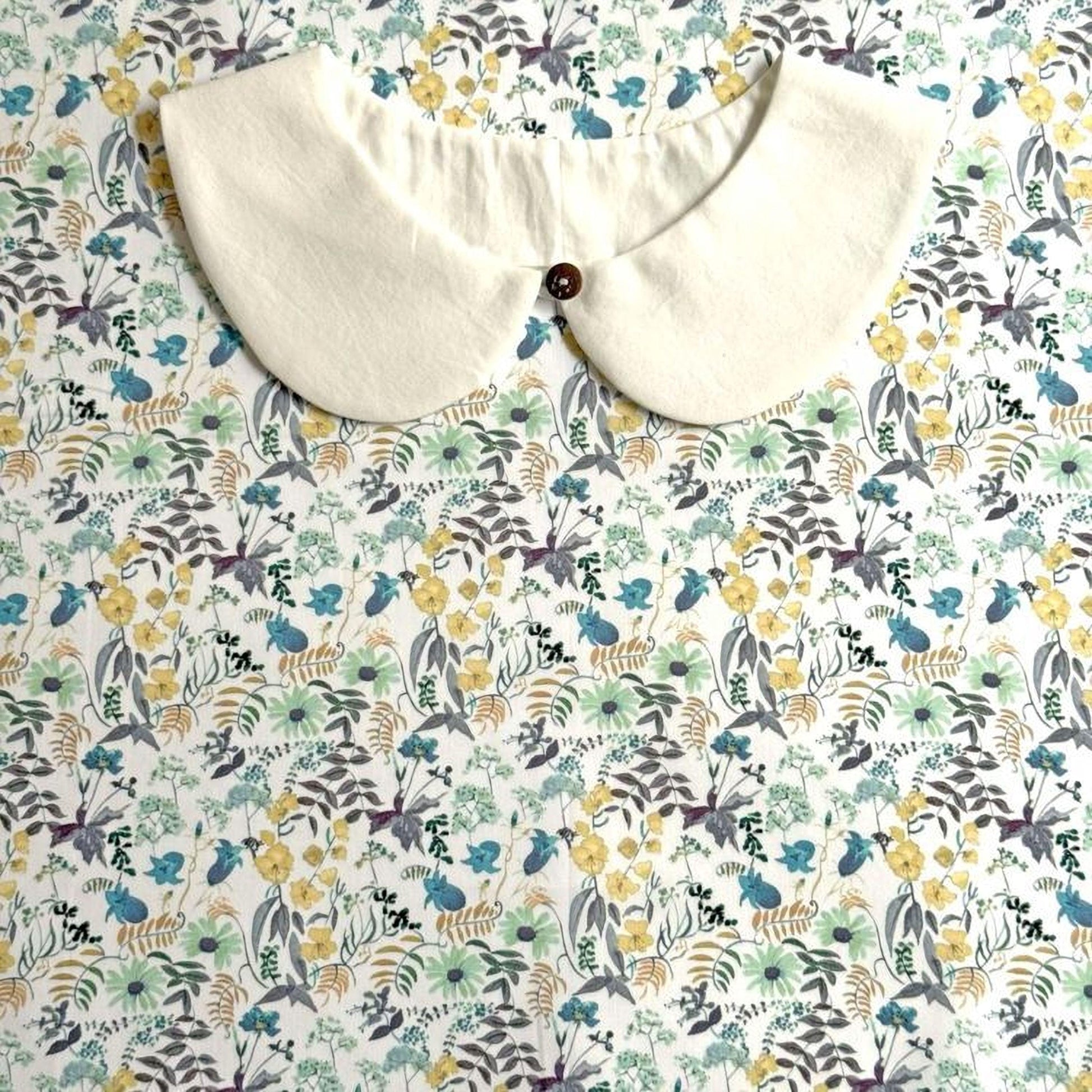a white collar with a button, placed on a floral print background.