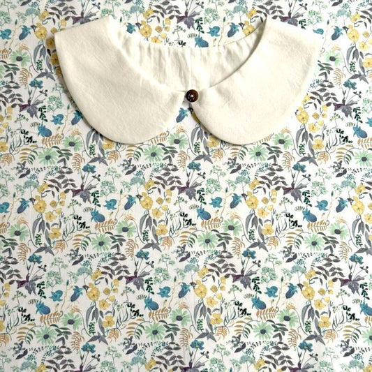 a white collar with a button, placed on a floral print background.